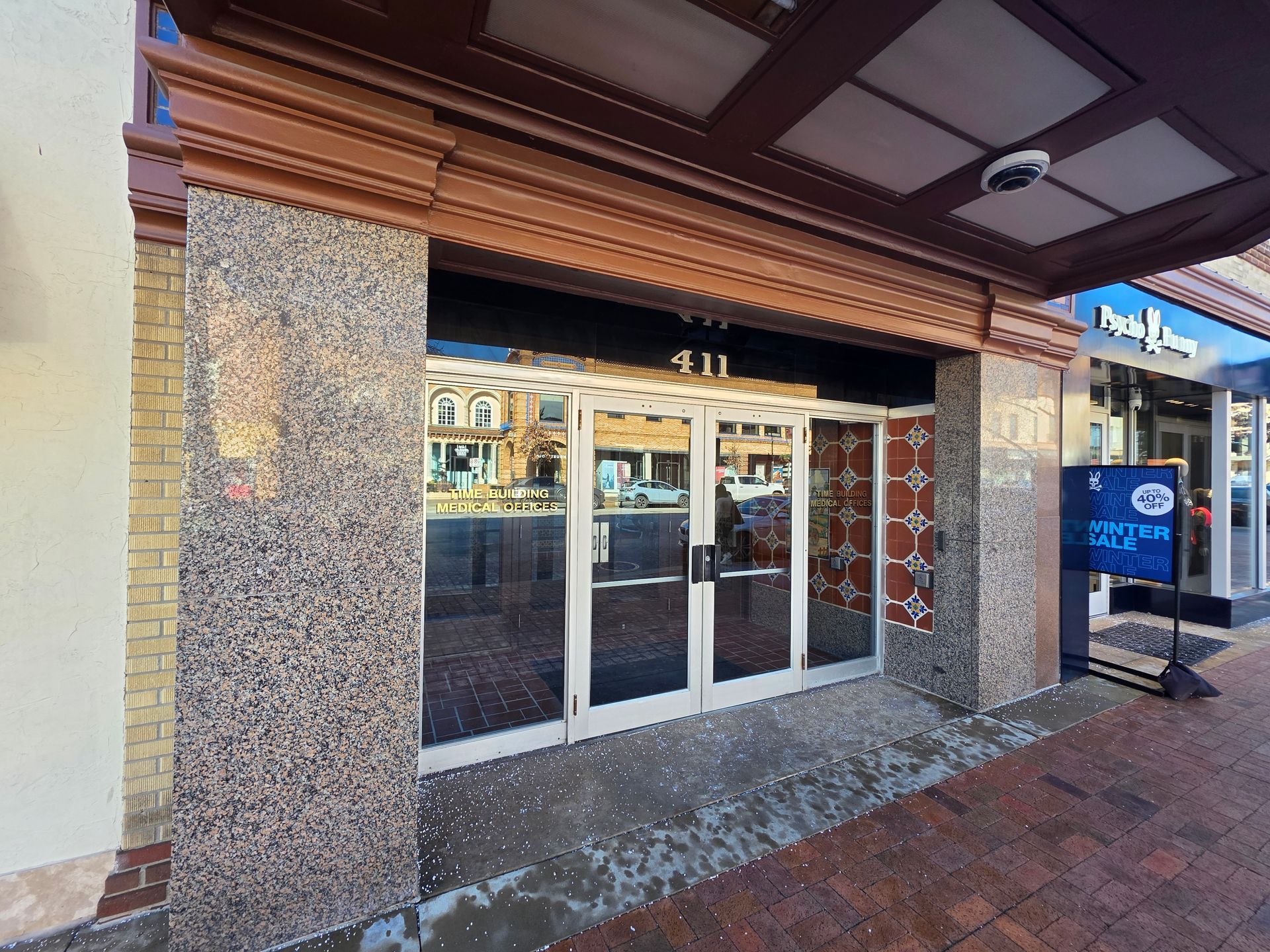 Storefront entrance at 411 with glass doors and tiled facade. A sign is placed near the entrance.