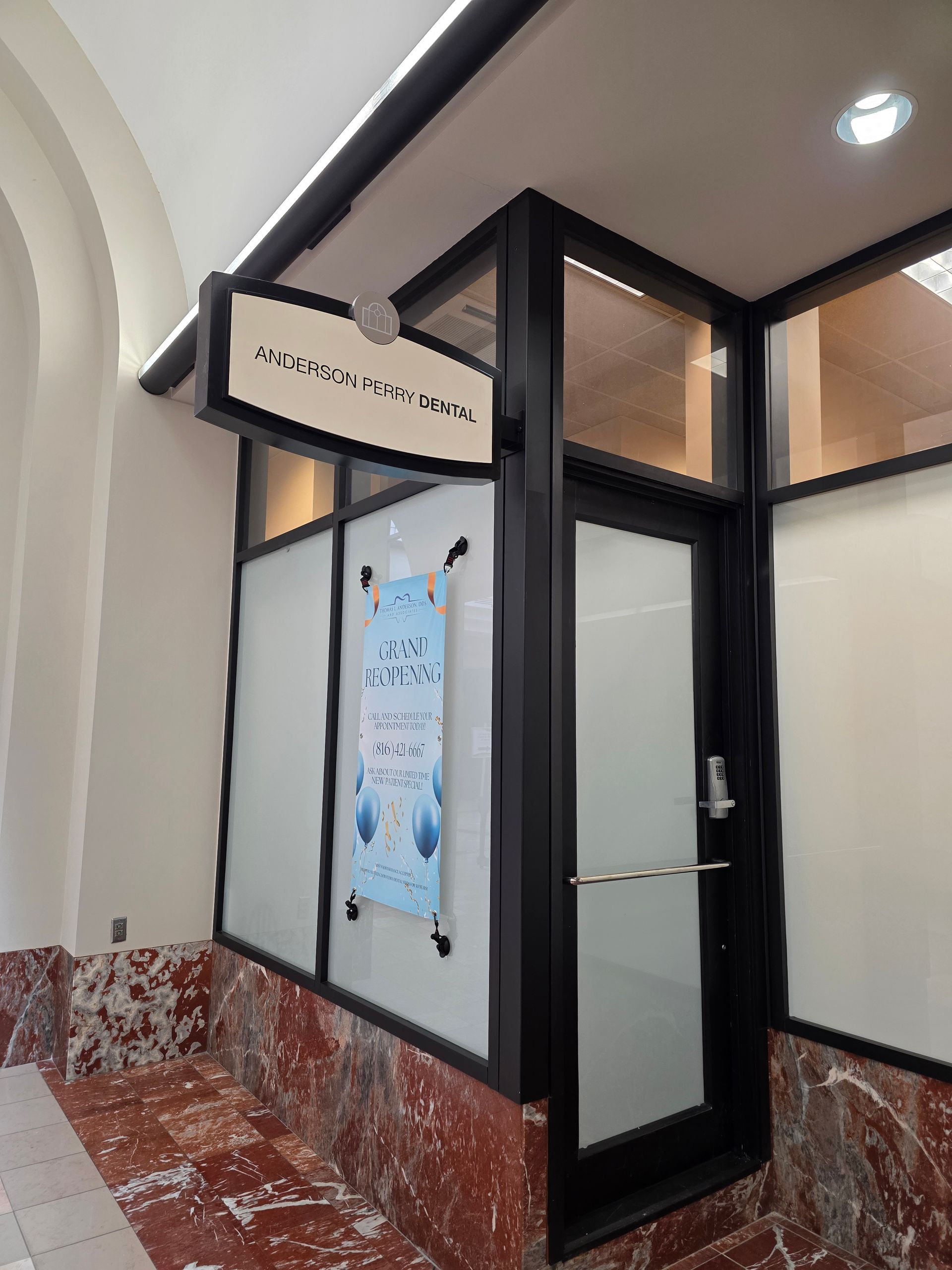 Entrance kiosk with frosted glass windows and door, a sign above says Anders Perry Dental