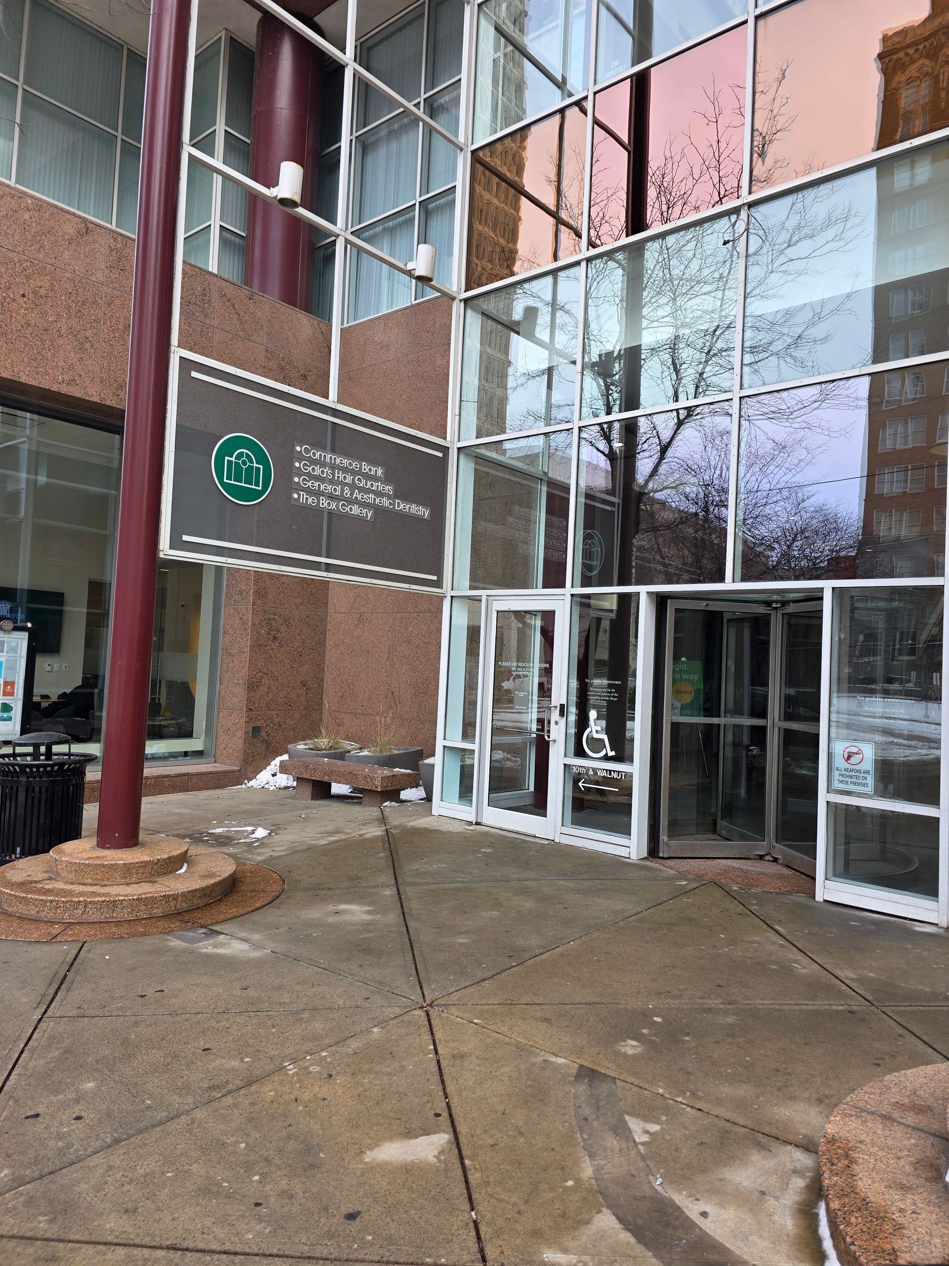 Entrance to Commerce building with glass doors and sign. Brown brick wall and sidewalk.