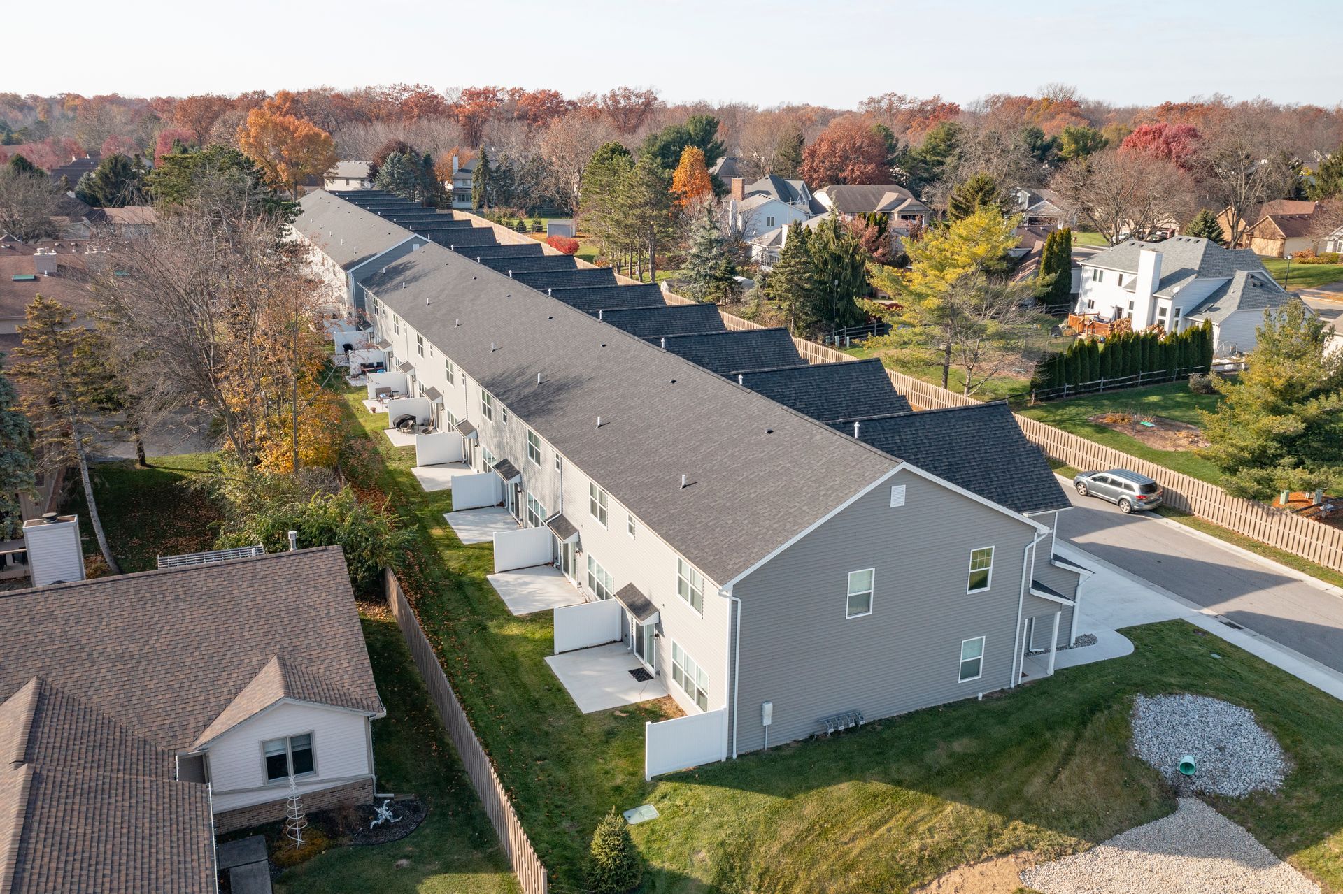 3/4 view of the row of houses, showing the side of the end unit, plus the backyards of all