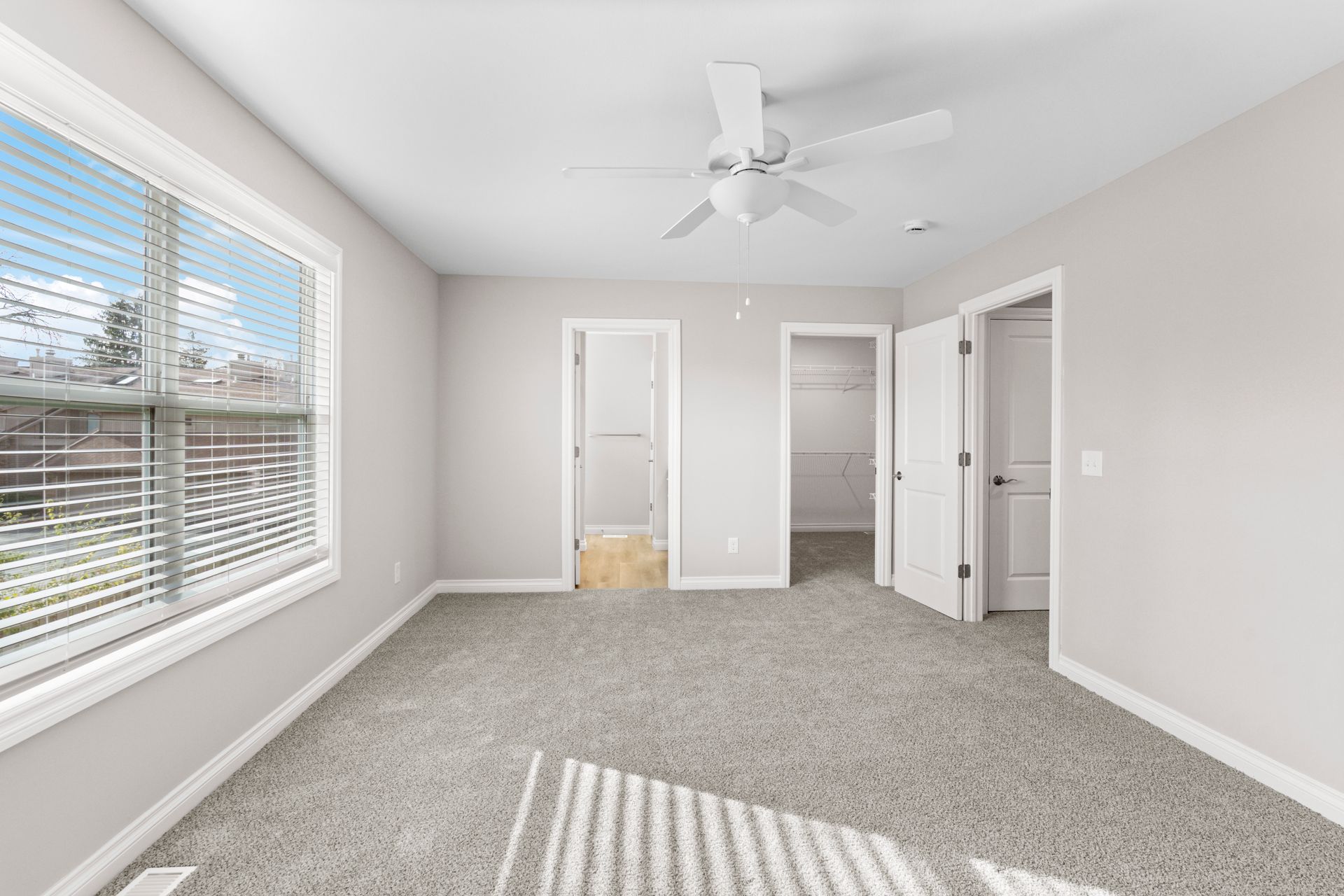 Photo of a master bedroom with a ceiling fan and walk-in closet