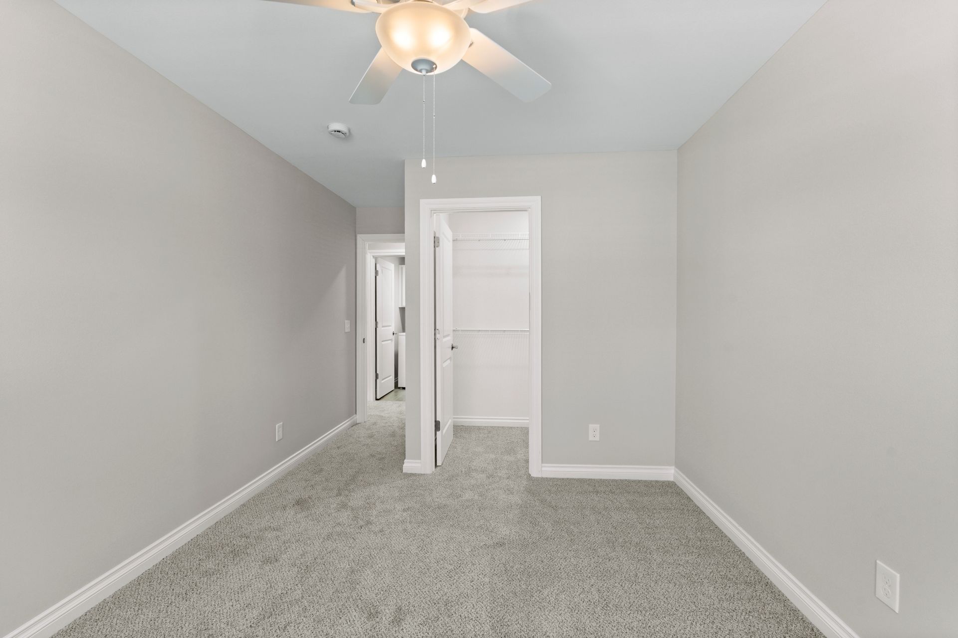 Photo of a bedroom with a walk-in closet and a ceiling fan