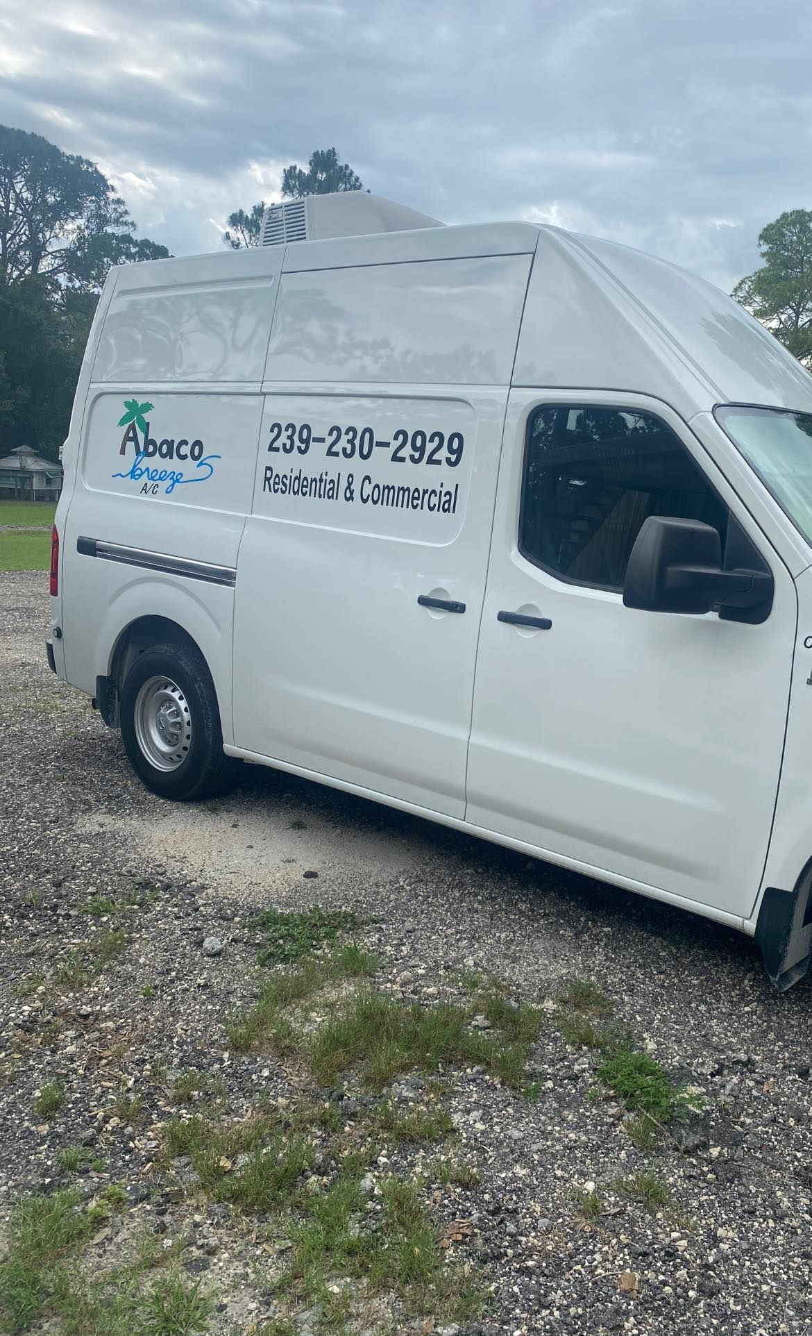 A white van is parked in a gravel lot.