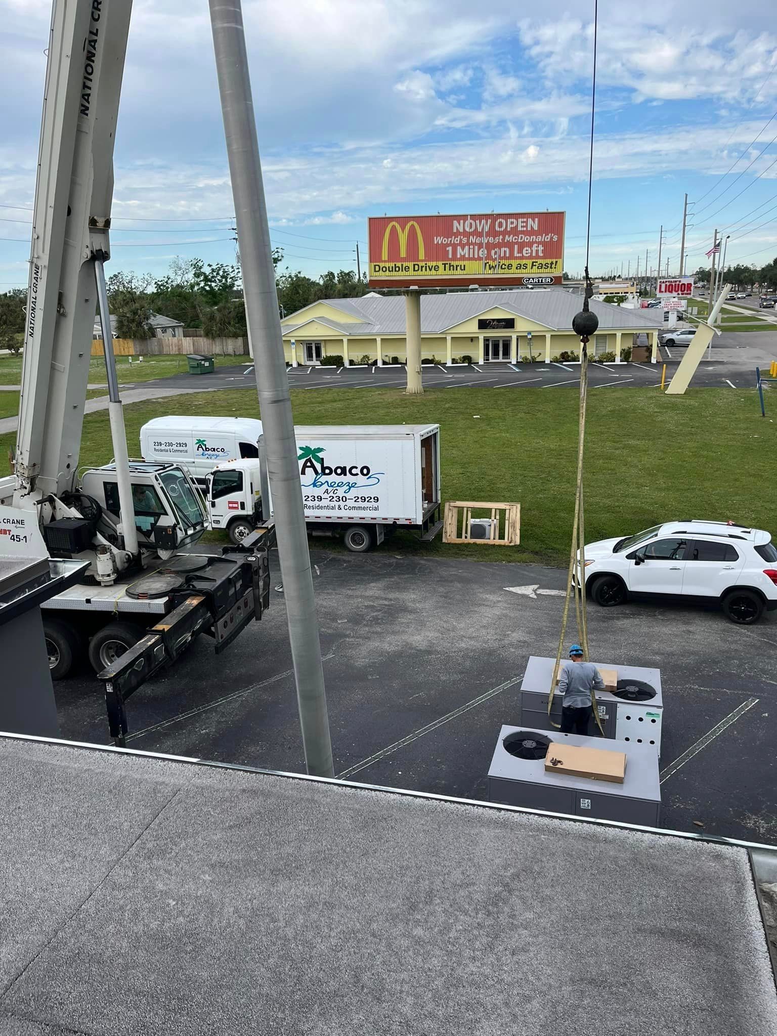 A large crane is sitting in a parking lot next to a mcdonald 's.