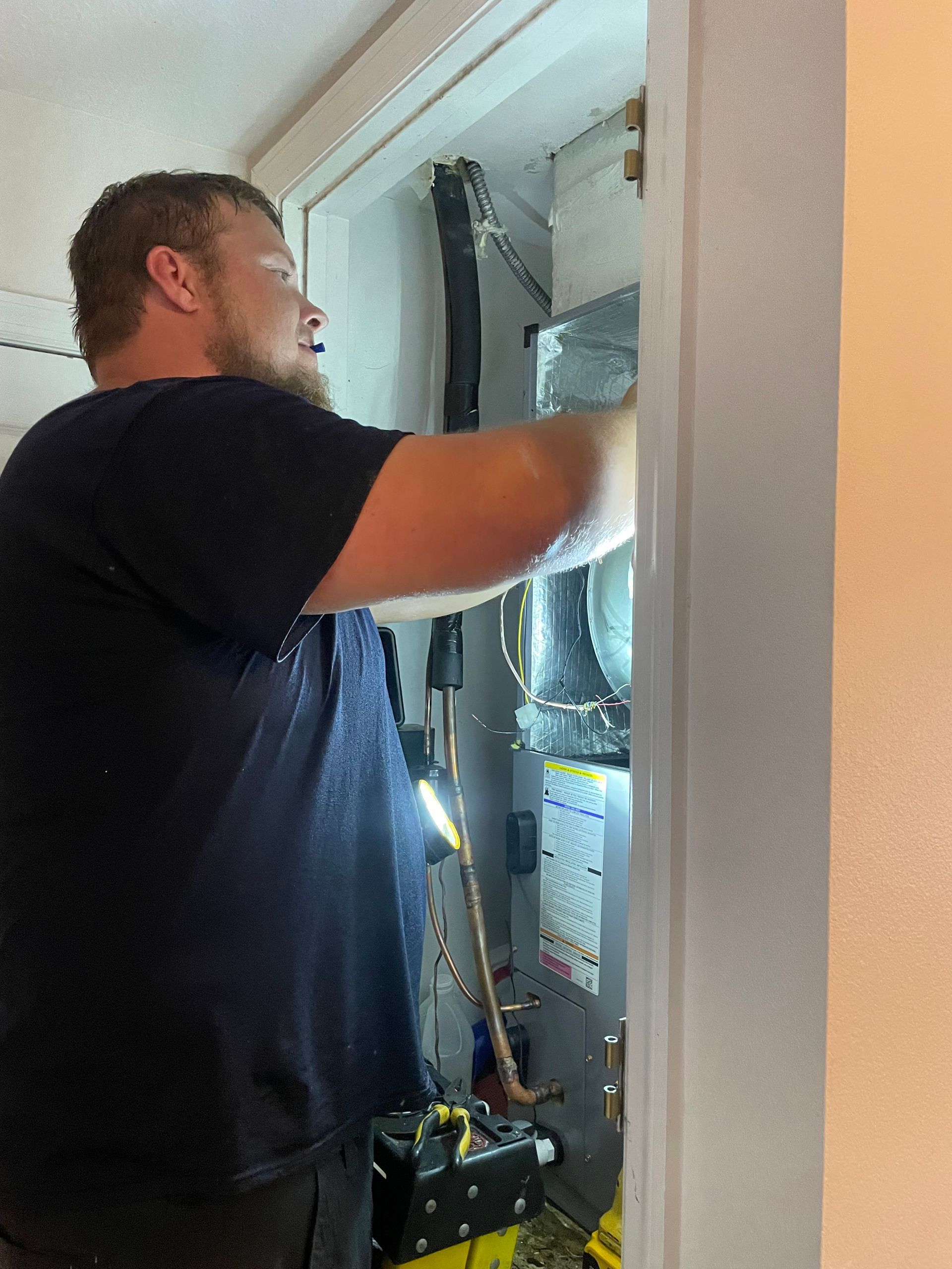 A man is working on an air conditioner in a room.