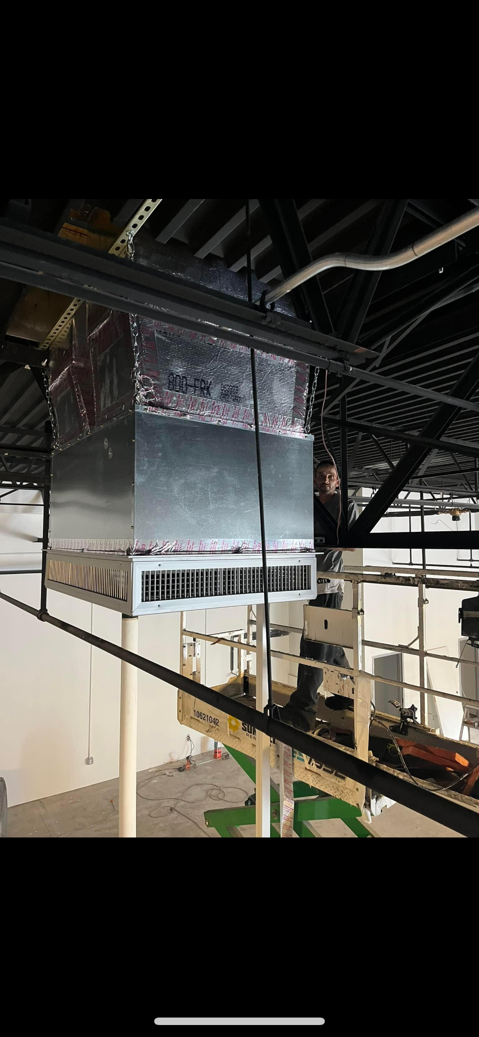 A large metal box is hanging from the ceiling of a building.