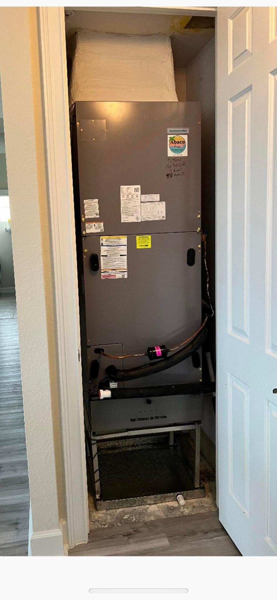 A refrigerator is sitting in a closet next to a door.