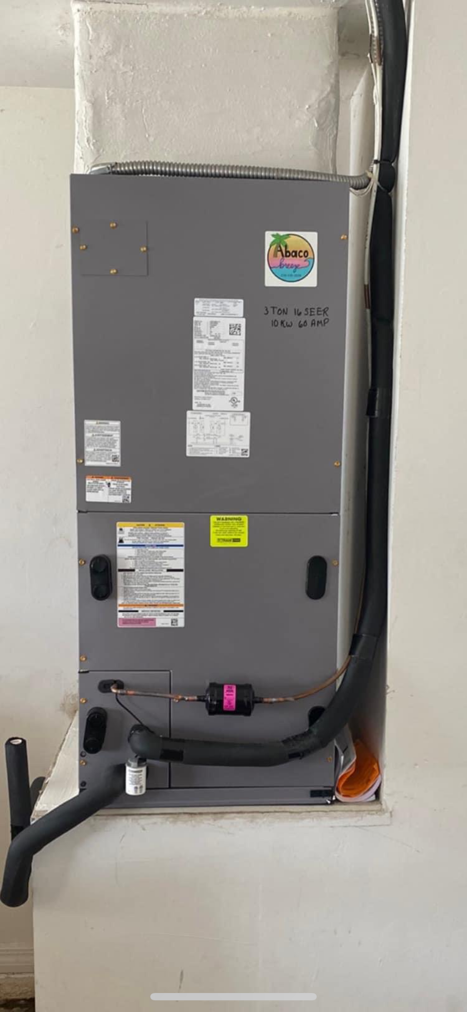 A gray air conditioner is hanging on a white wall in a room.