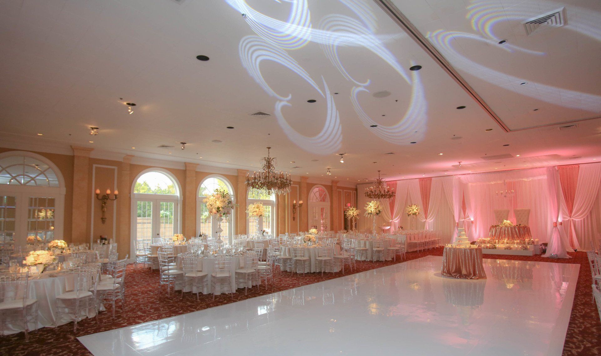 A large room with tables and chairs and a white dance floor.
