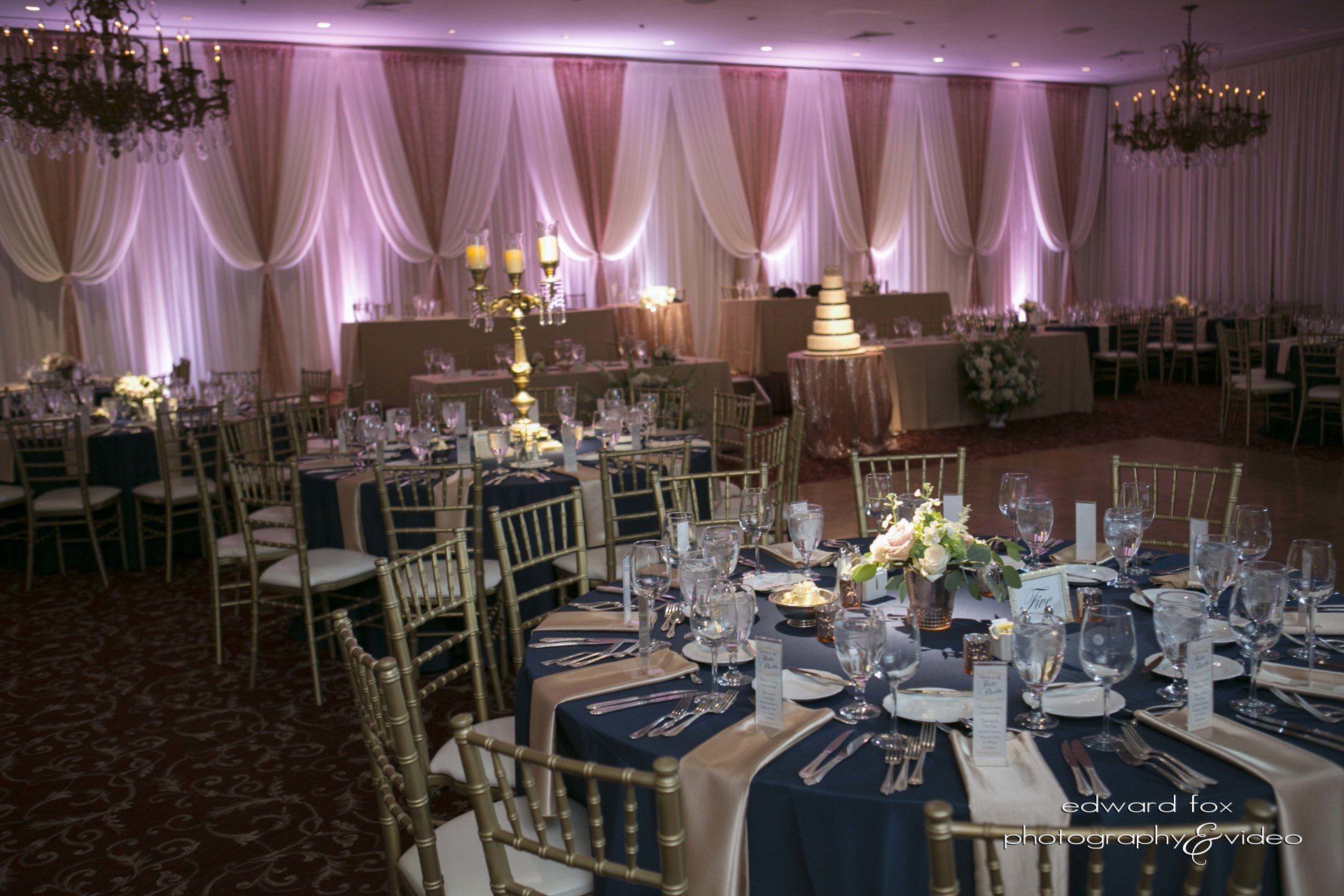 A large room with tables and chairs set up for a wedding reception.