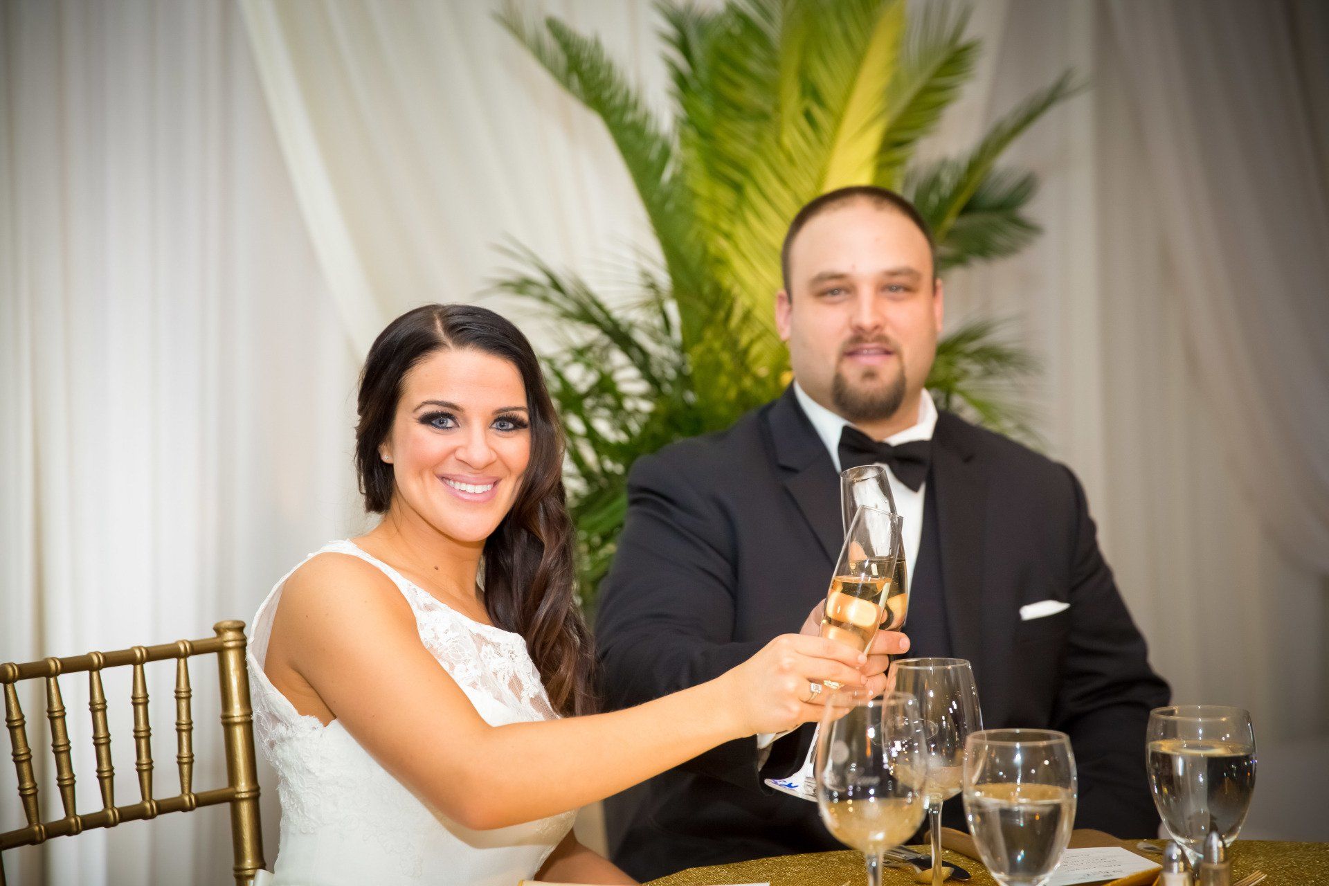 A bride and groom are toasting with champagne at their wedding reception.