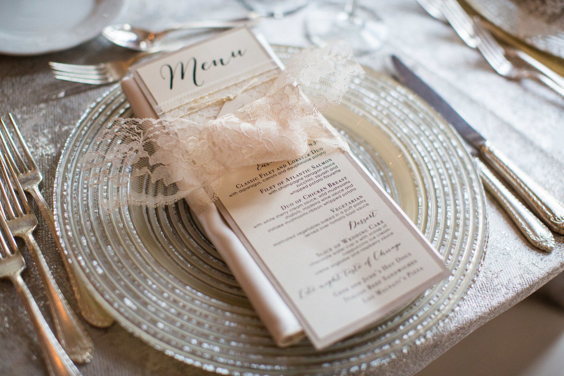 A menu is sitting on top of a silver plate on a table.