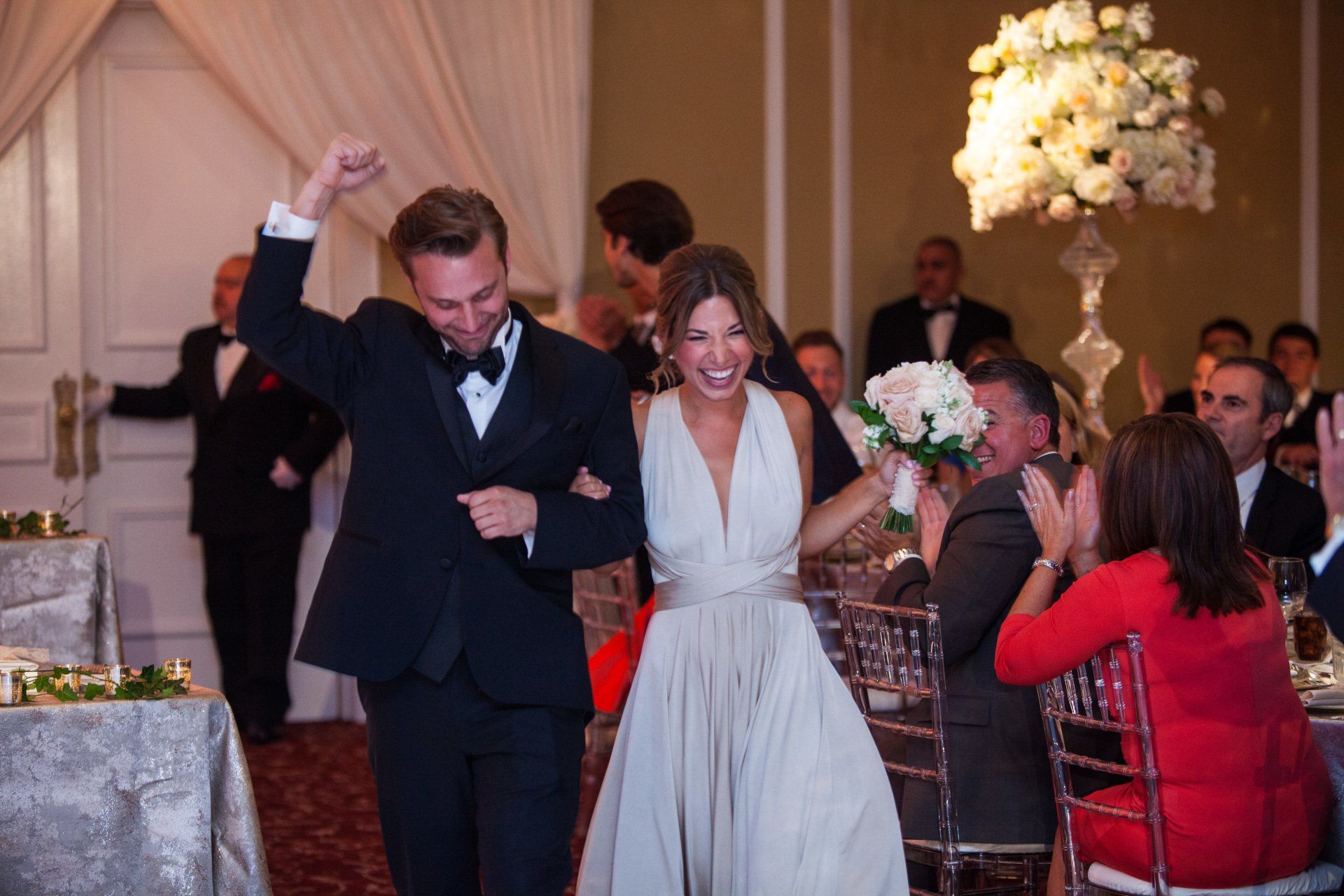 A bride and groom are walking into their wedding reception