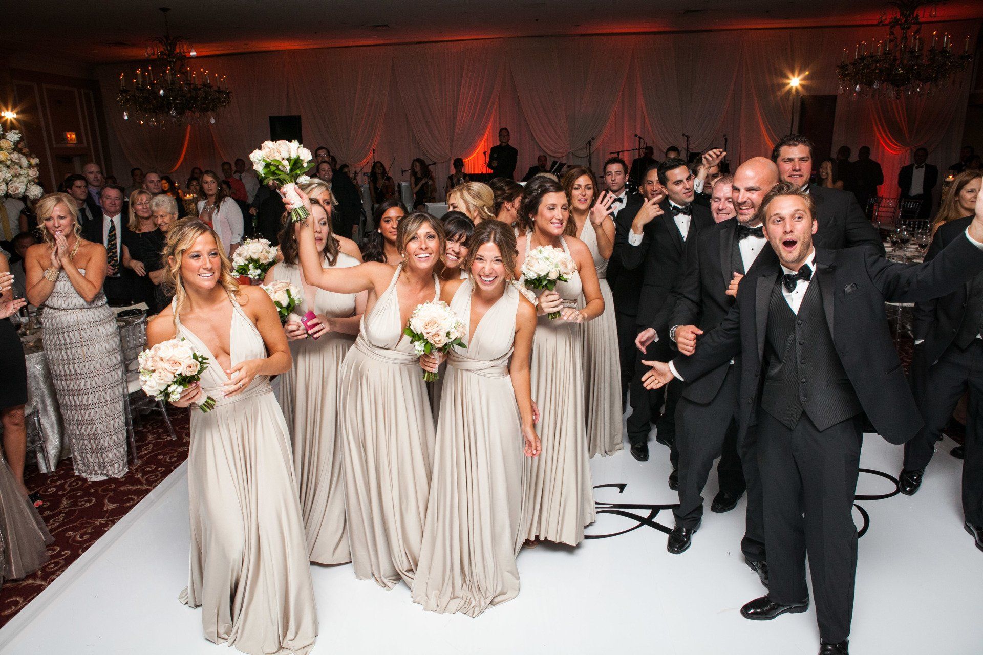 A group of people are standing on a white dance floor.