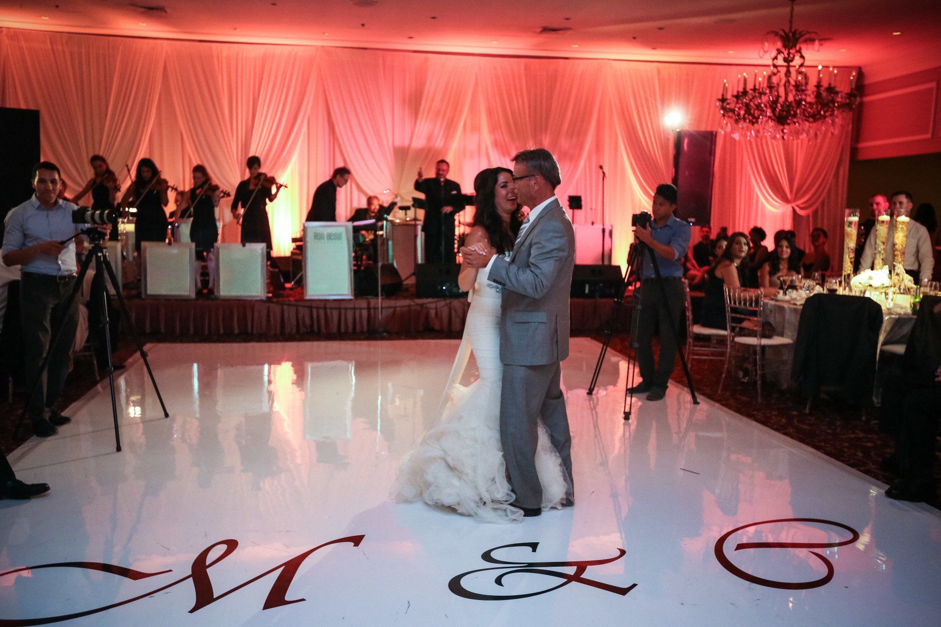 A bride and groom are dancing on a white dance floor