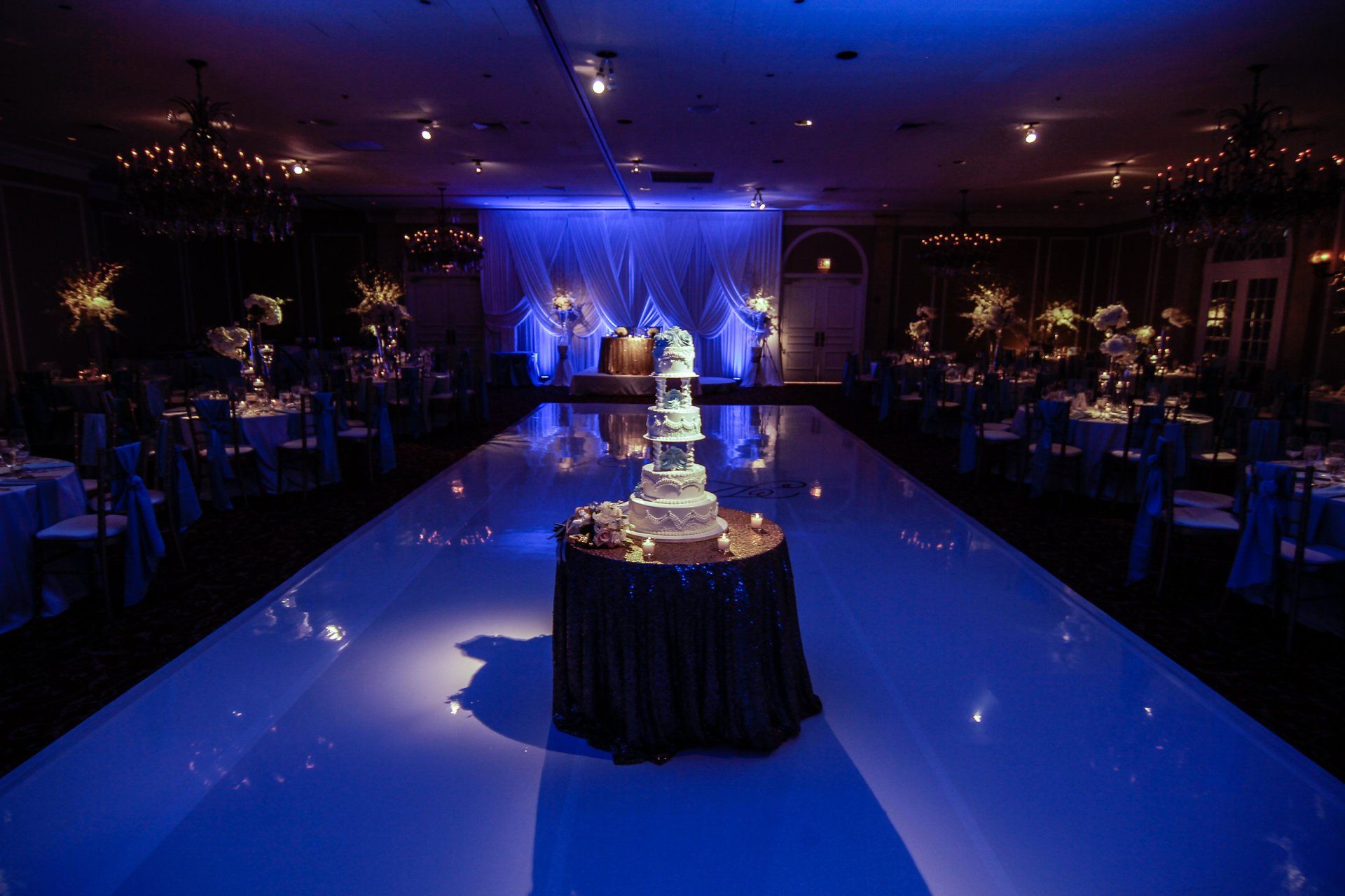 A wedding cake is on a table in the middle of a dance floor.