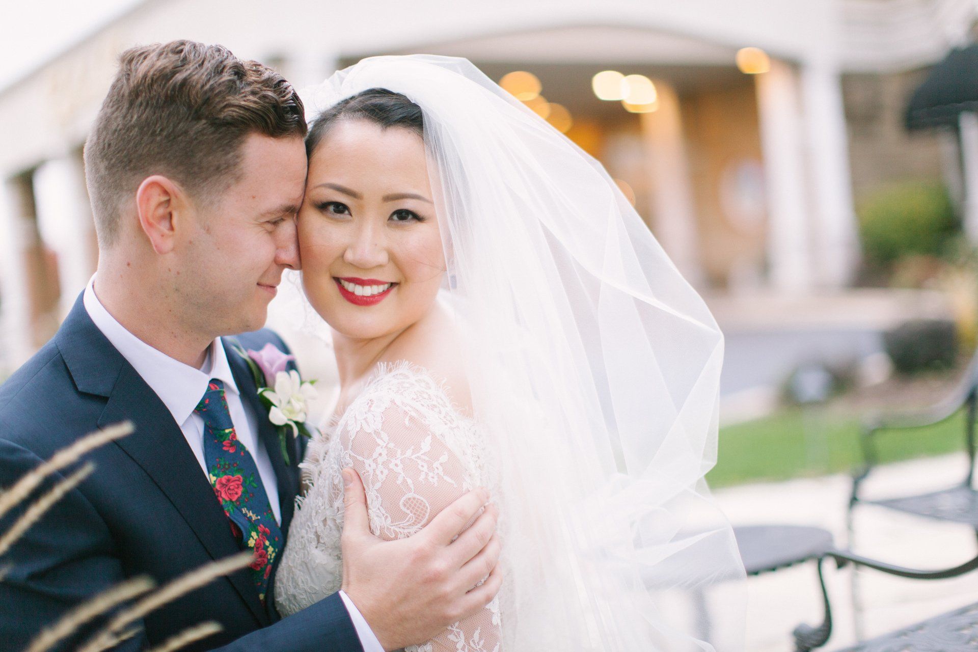 A bride and groom are posing for a picture in front of a building.