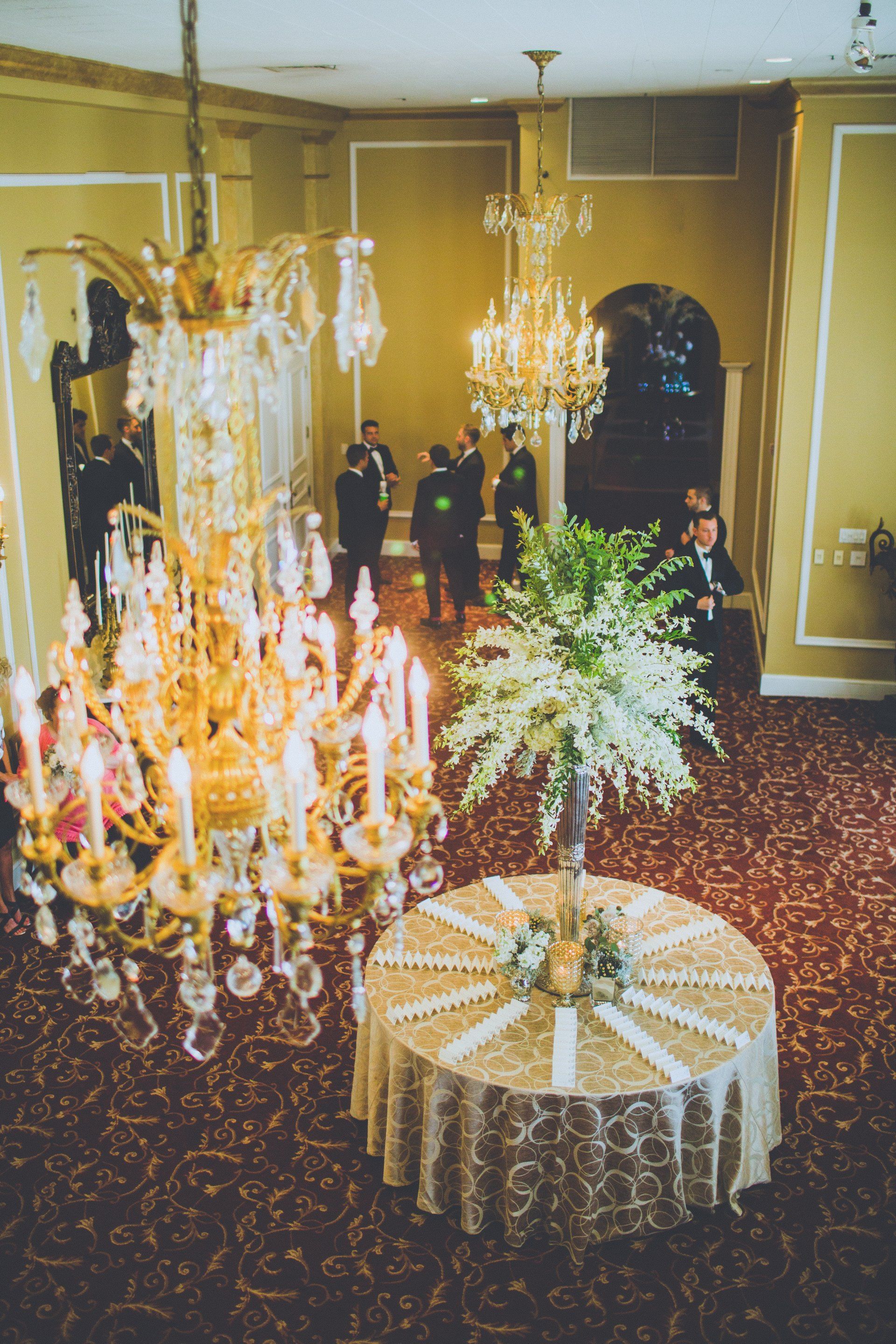 A room with a chandelier and a table with flowers on it.