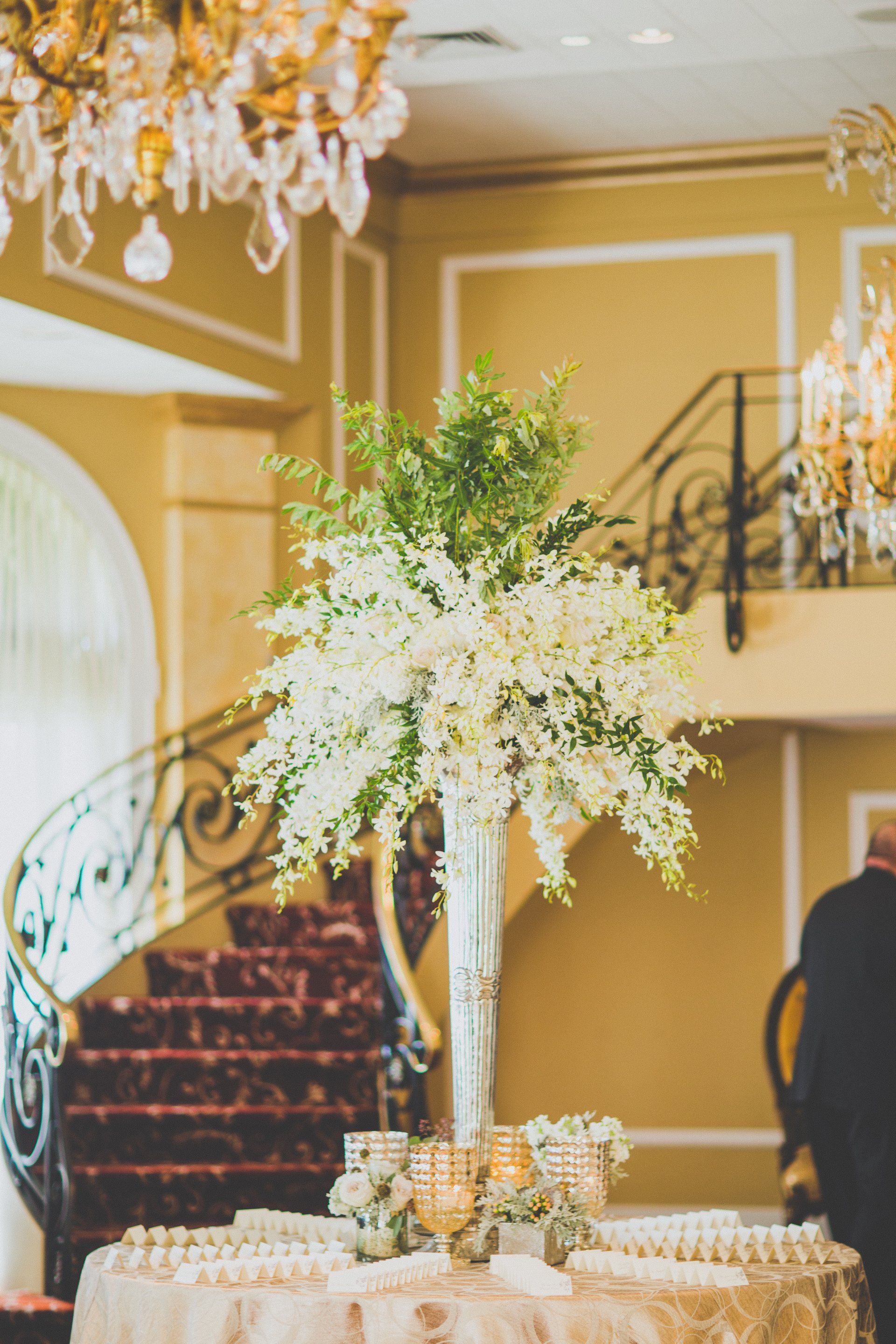 A table with candles and flowers on it in a room with stairs.