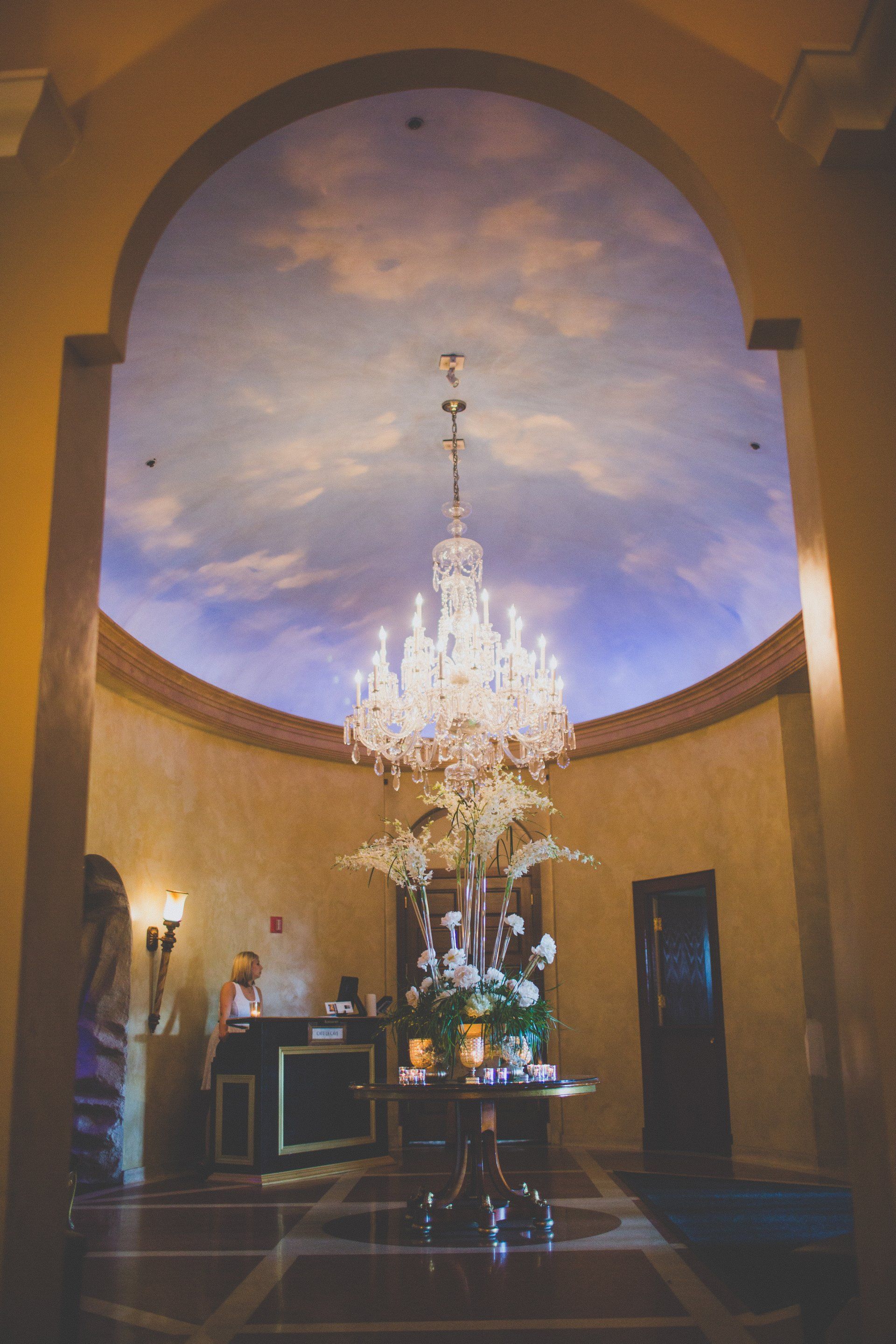 A large chandelier is hanging from the ceiling of a hotel lobby