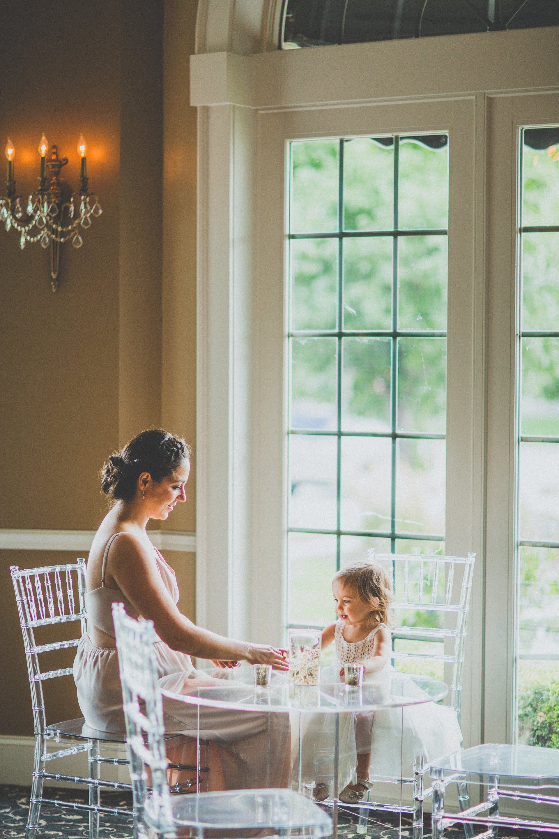 A woman is sitting at a table with a little girl.