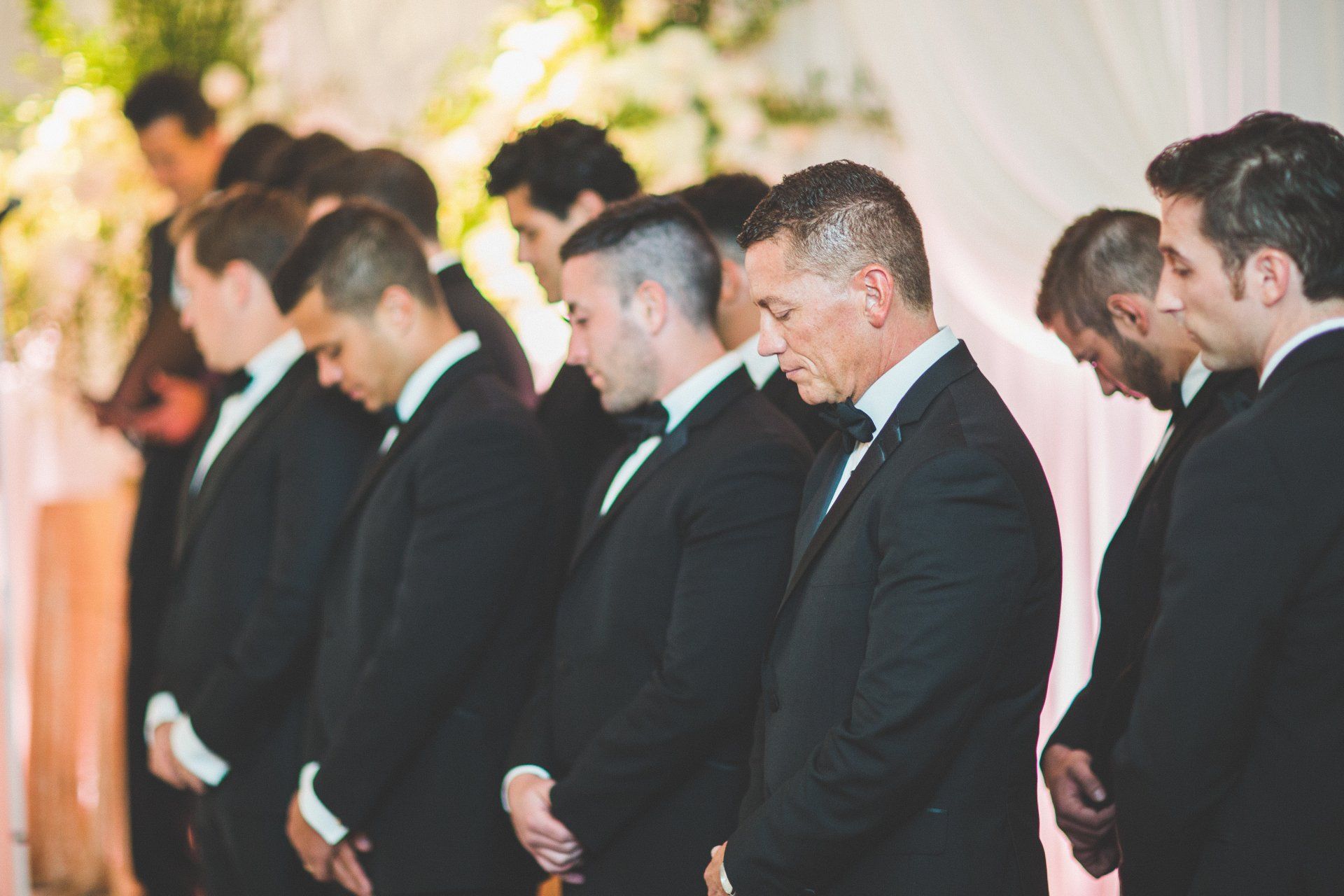 A group of men in suits and bow ties are standing in a line.
