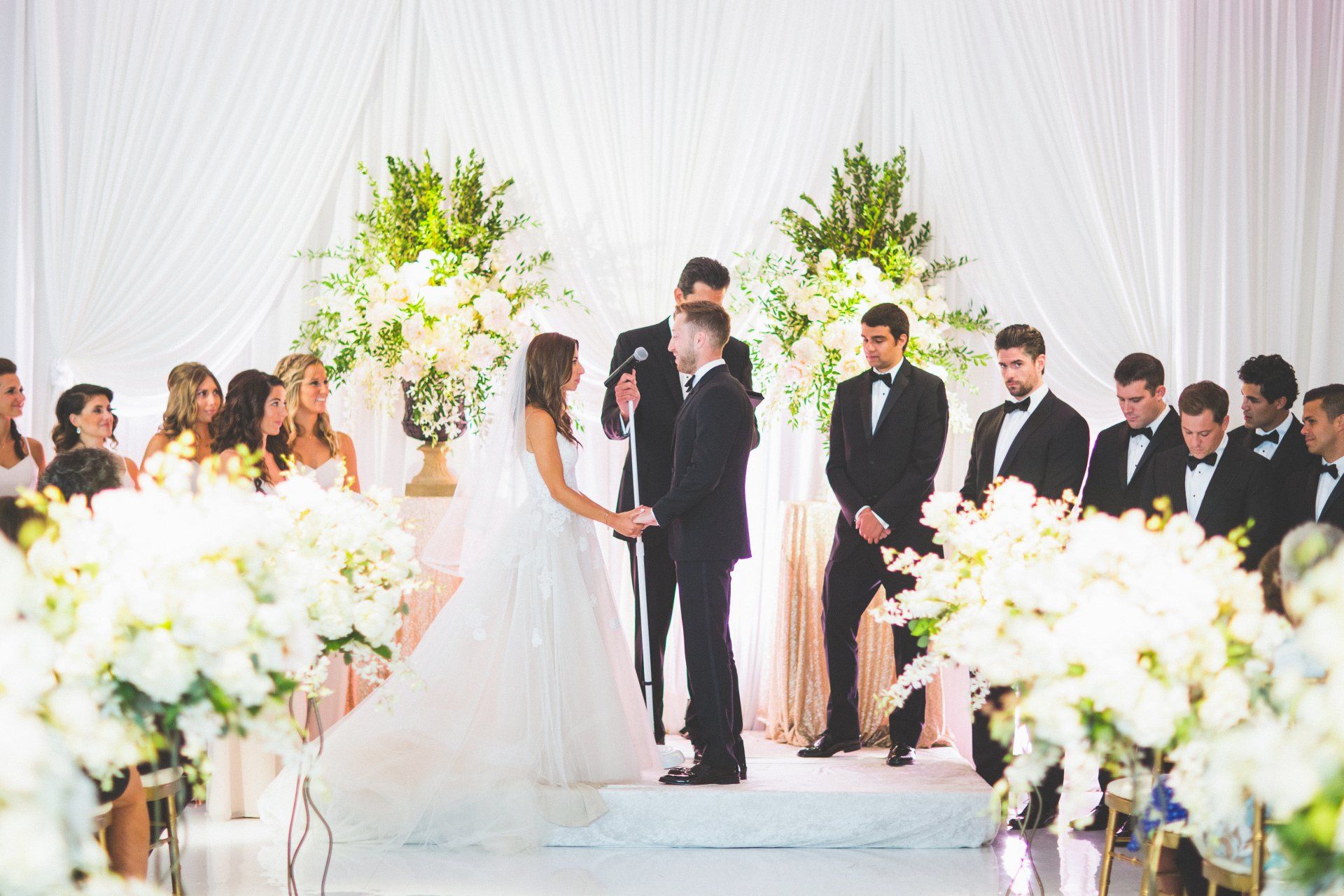 A bride and groom are holding hands during their wedding ceremony.