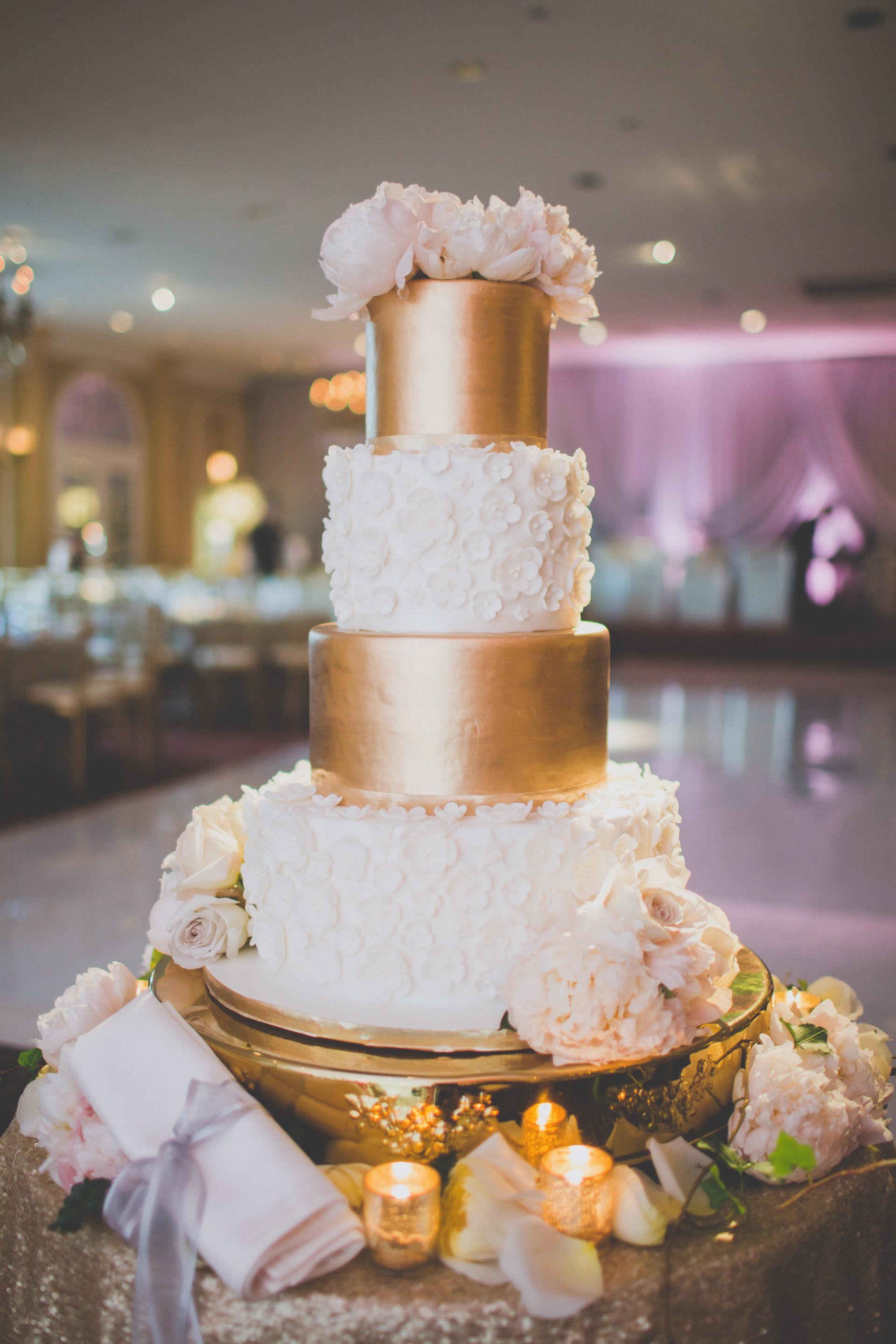 A white and gold wedding cake is sitting on top of a table.