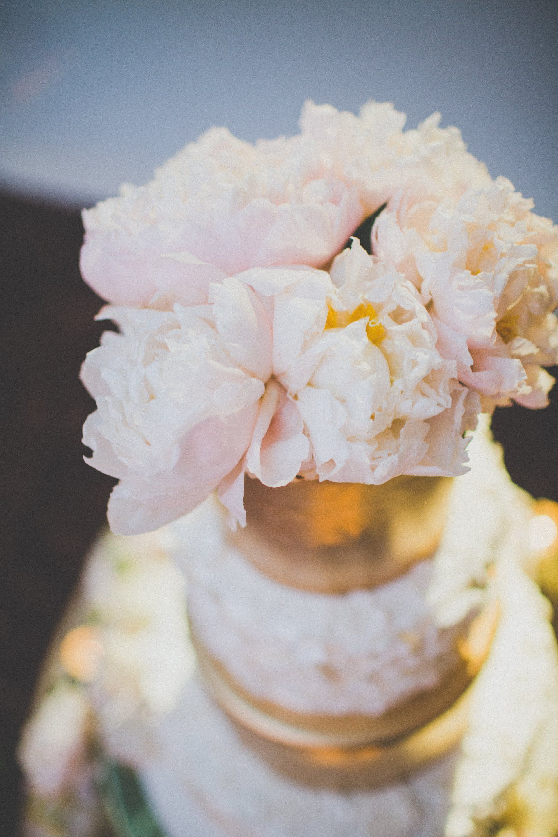 A close up of a wedding cake with a pink flower on top.