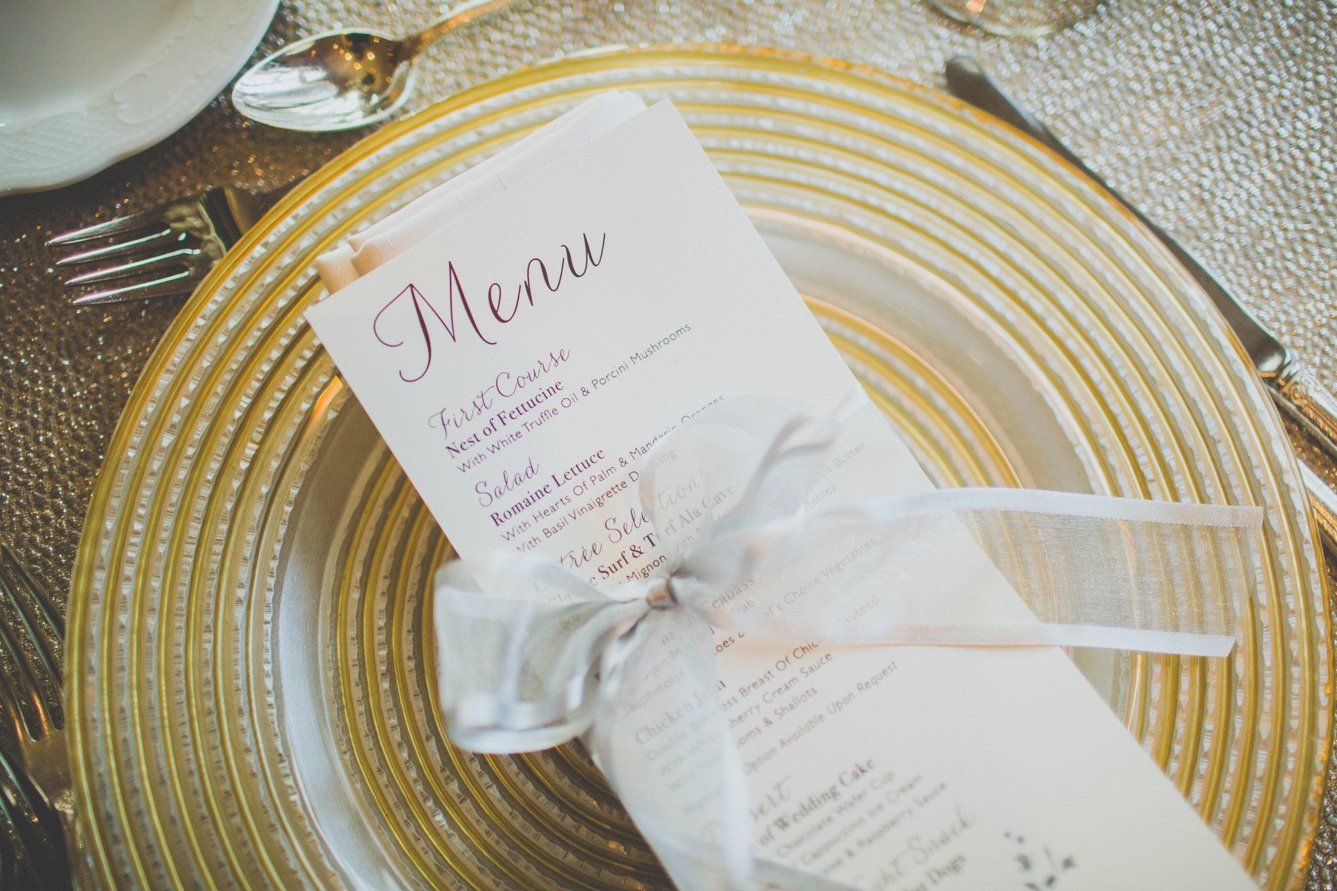 A menu is sitting on top of a gold plate on a table.