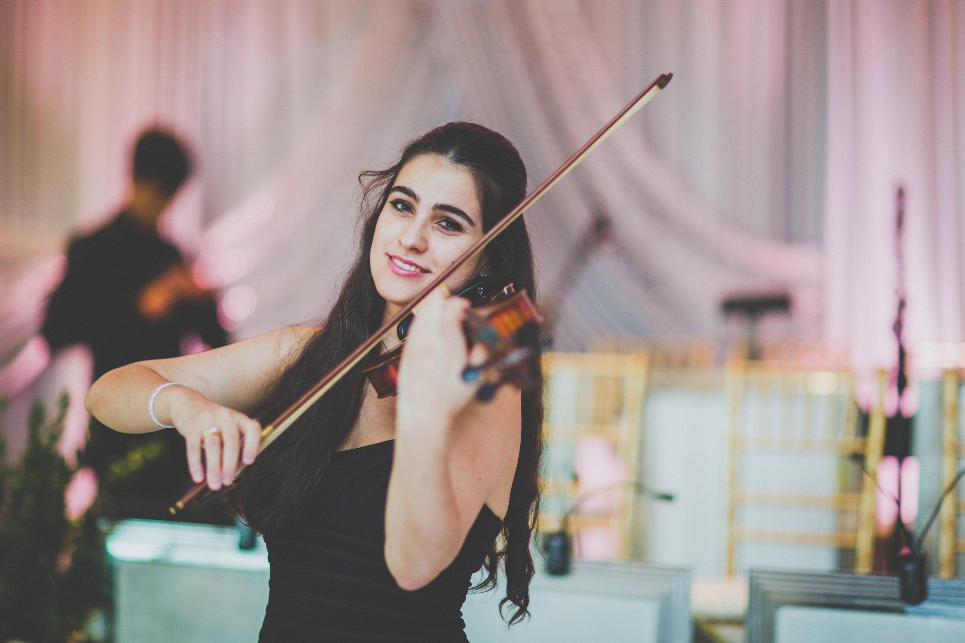 A woman in a black dress is playing a violin.