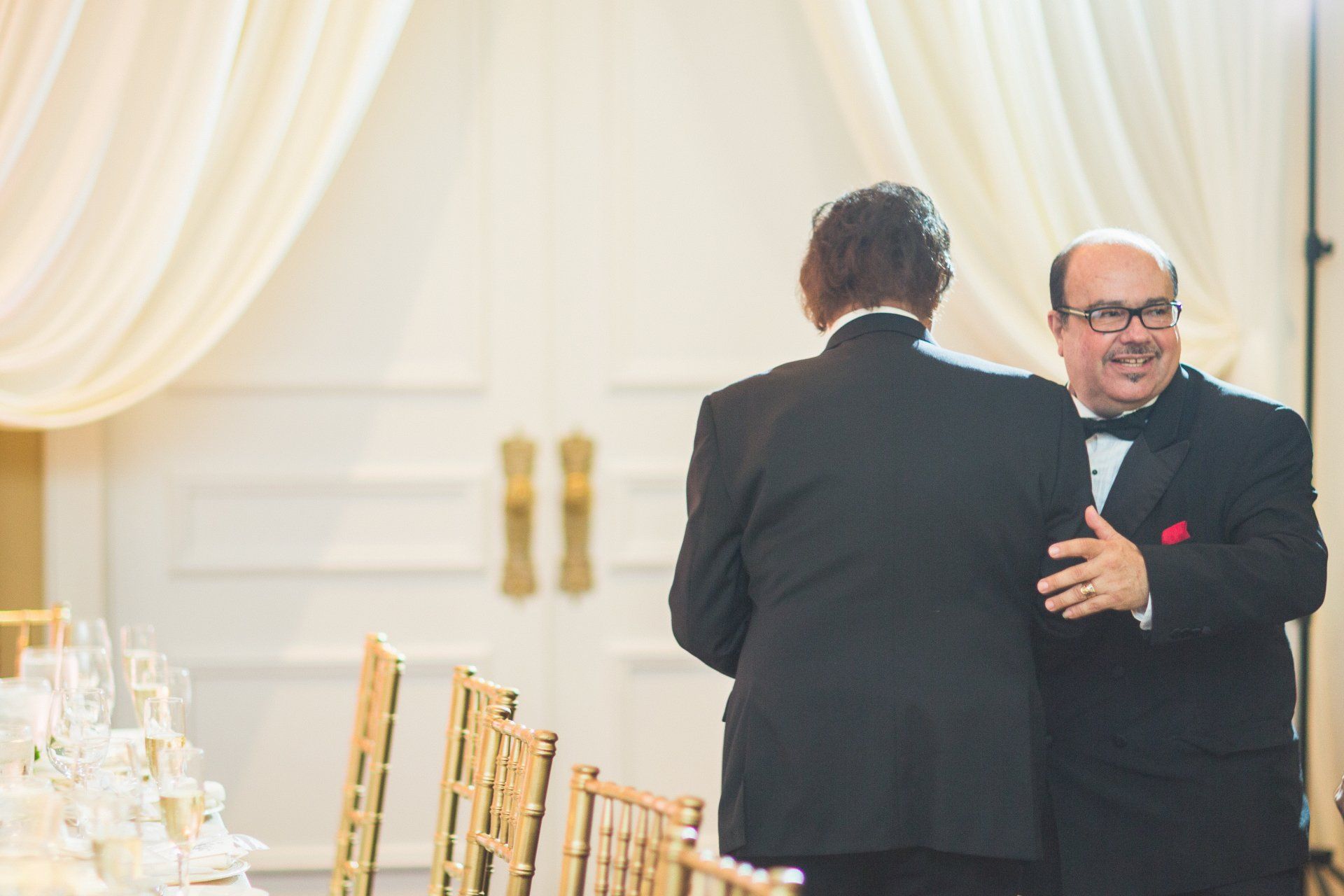 Two men in tuxedos are standing next to each other in a room.