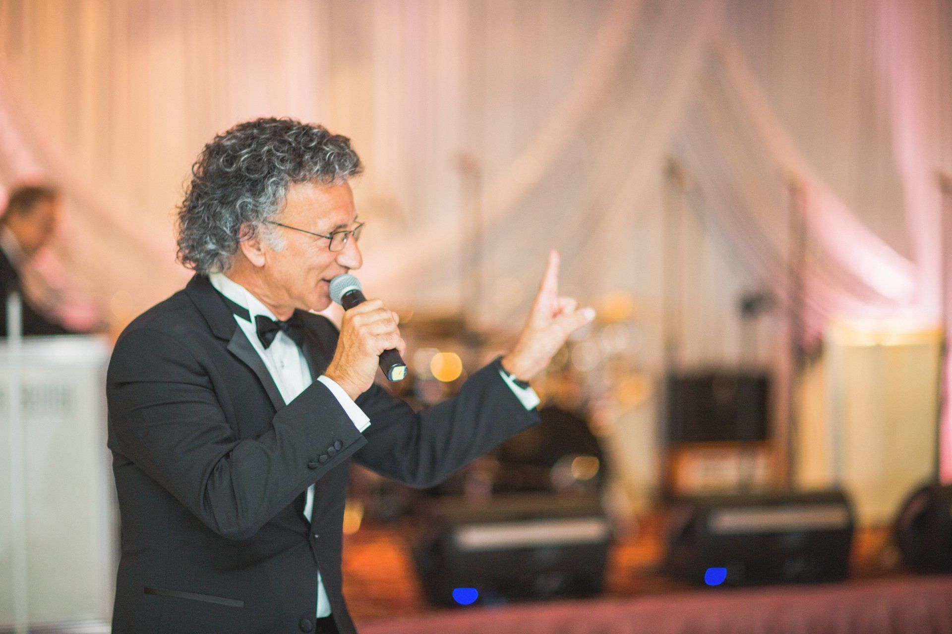 A man in a tuxedo is singing into a microphone.