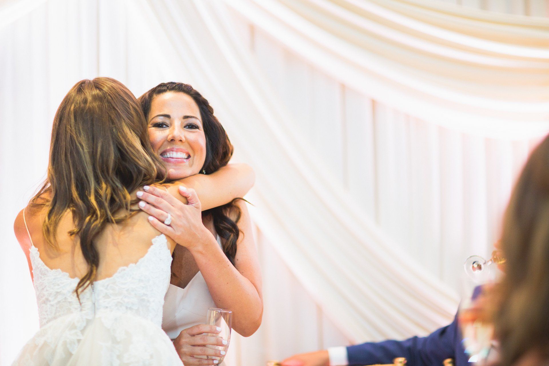 A bride and her mother are hugging each other at a wedding reception.