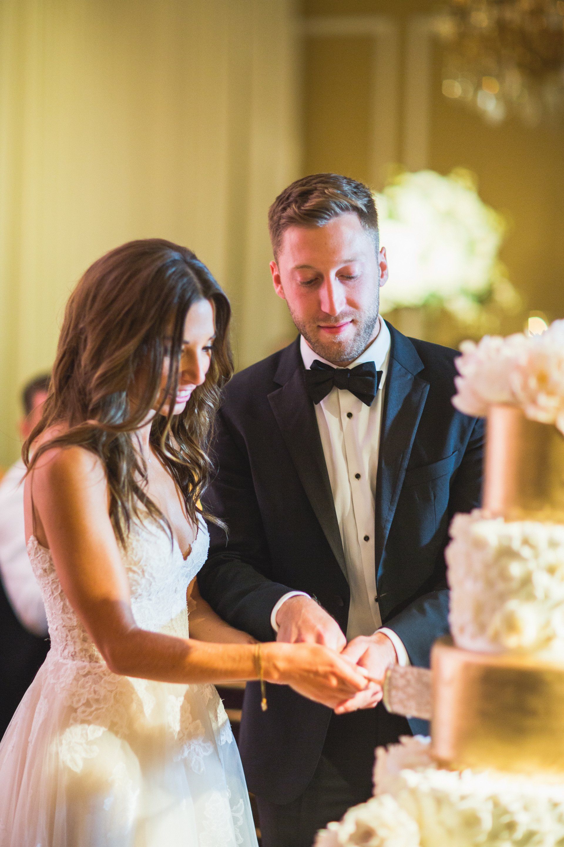 A bride and groom are cutting their wedding cake together.