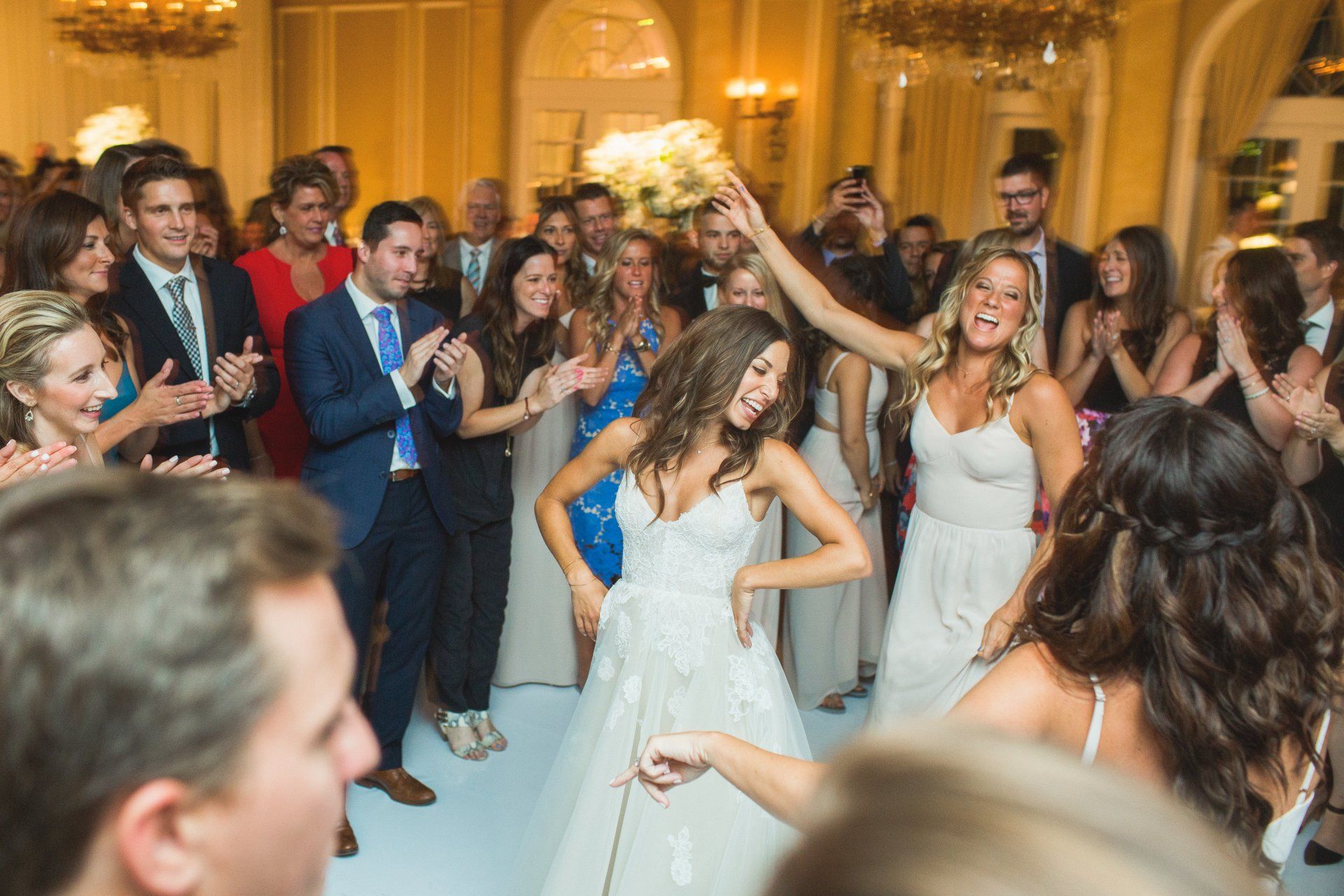A group of people are dancing at a wedding reception.