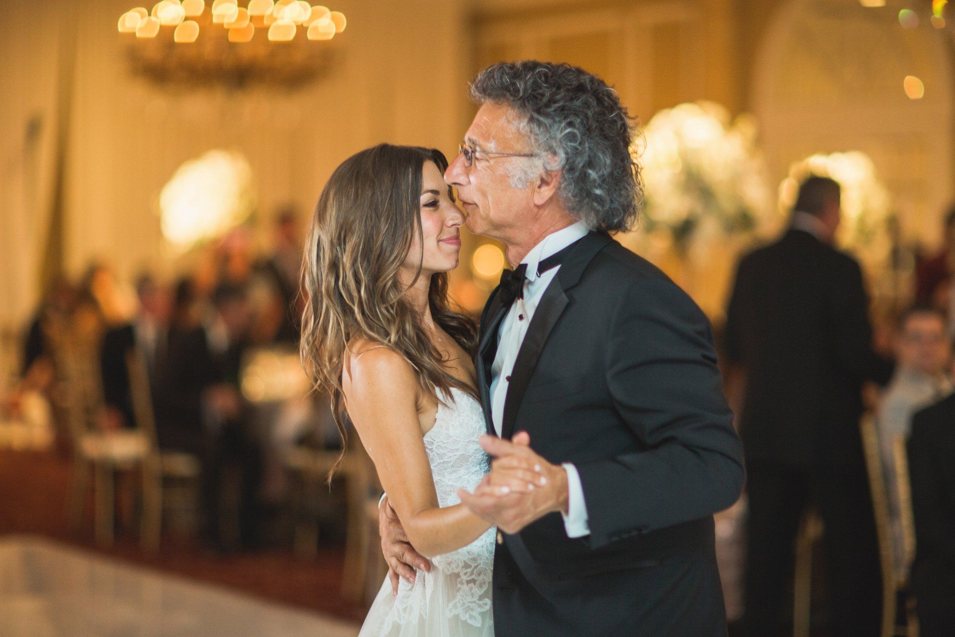 A bride and her father are dancing together at a wedding reception.