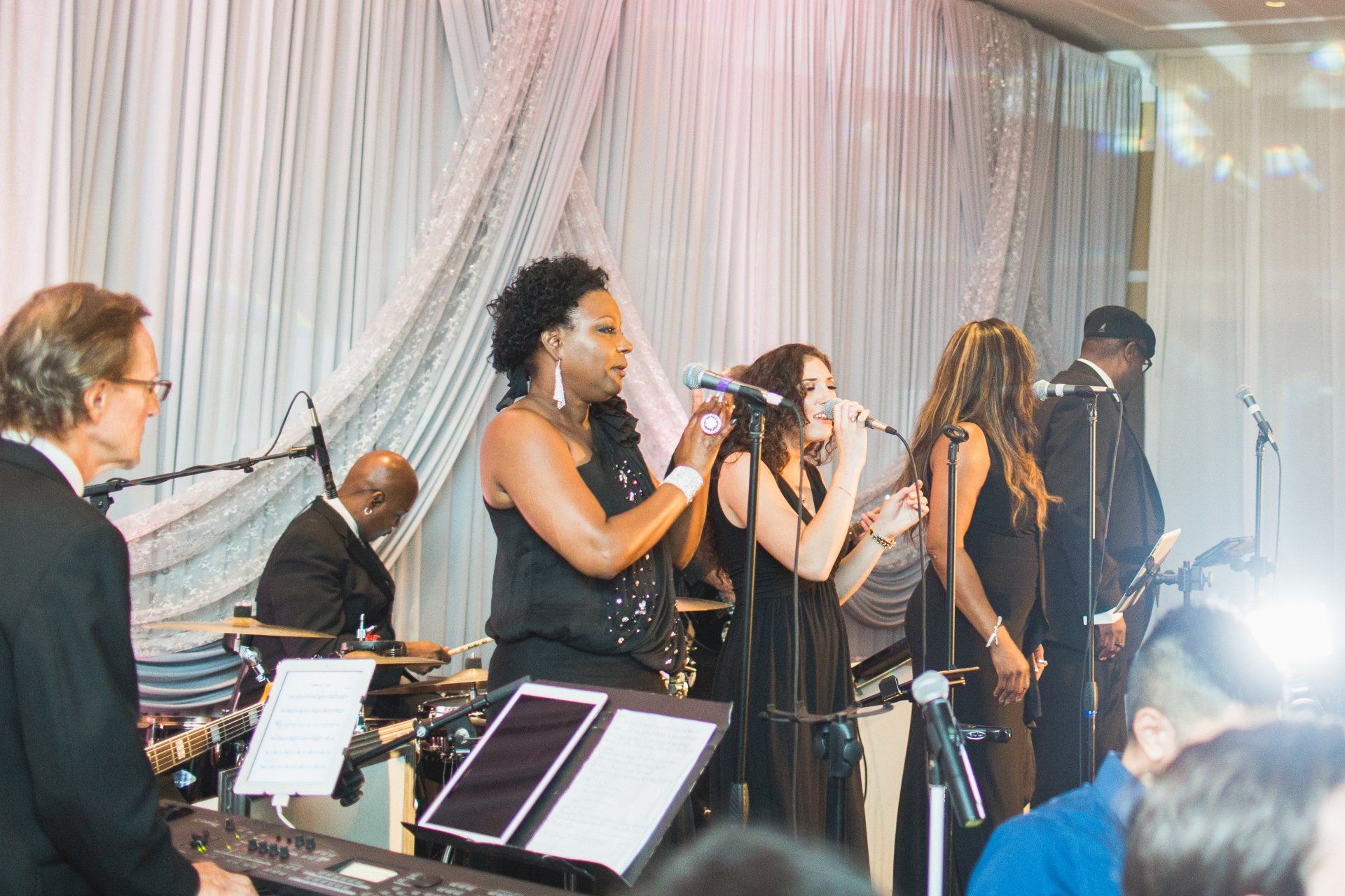 A group of people are singing into microphones on a stage.