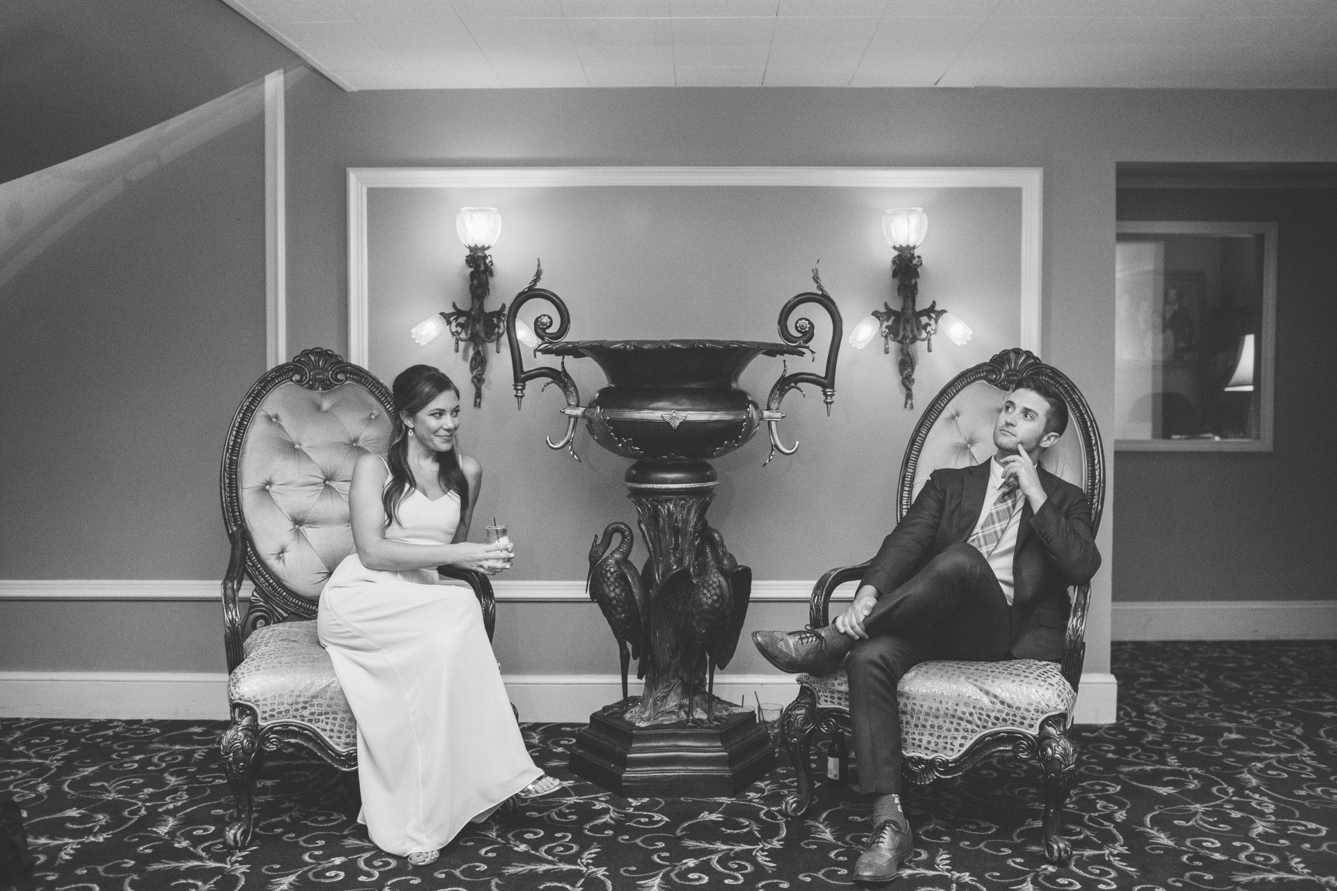A black and white photo of a bride and groom sitting in chairs.