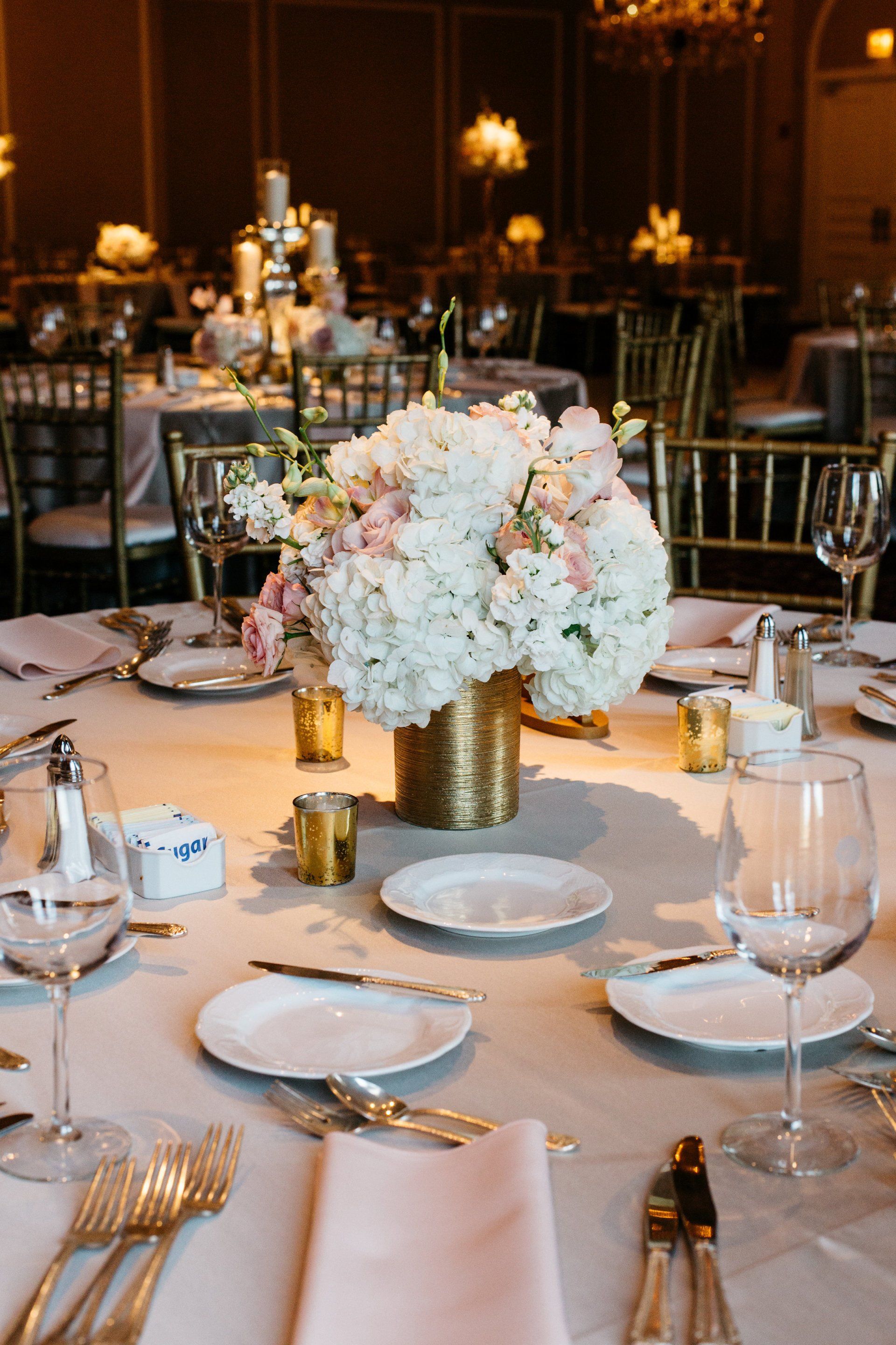 A table set for a wedding reception with a vase of flowers on it.