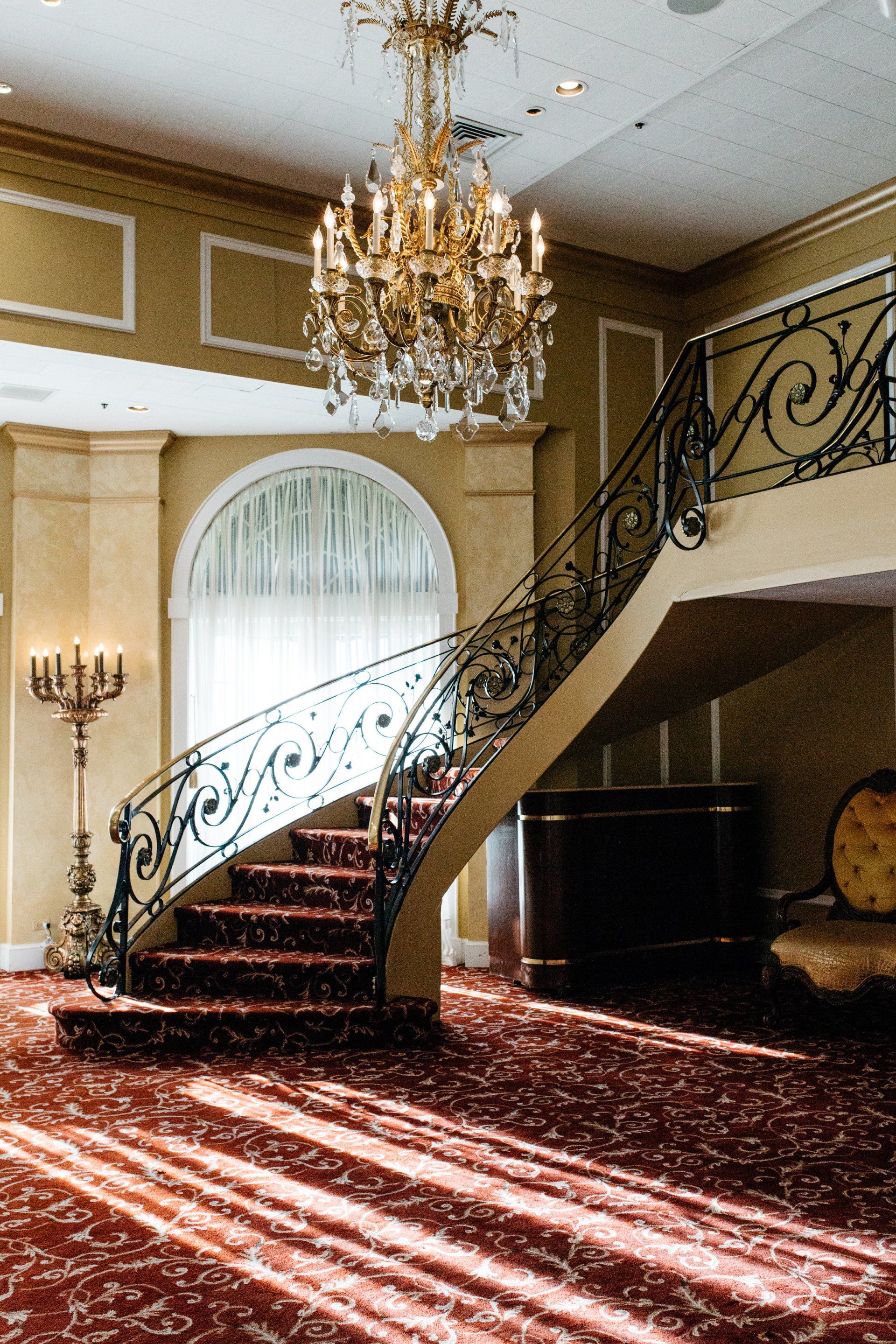 A staircase with a wrought iron railing and a chandelier hanging from the ceiling