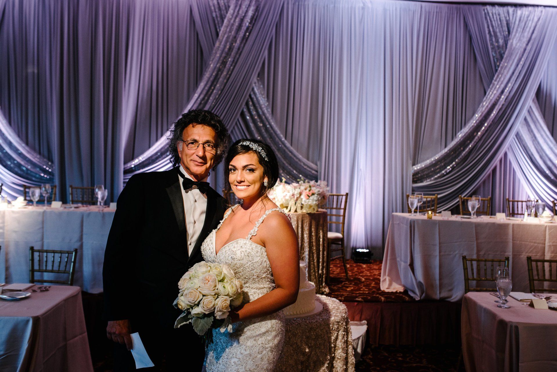 A bride and groom are posing for a picture at their wedding reception.