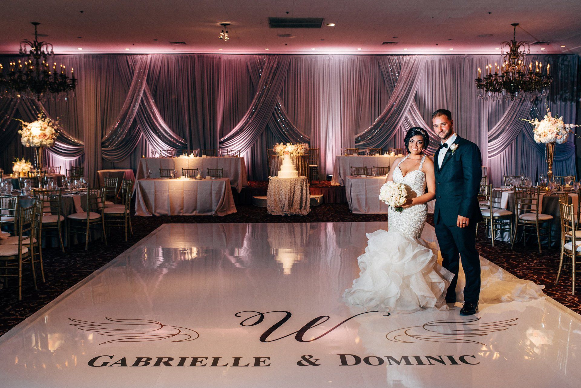 A bride and groom are standing on a white dance floor at their wedding reception.