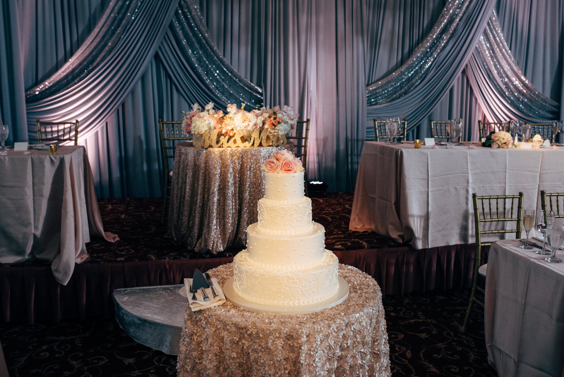 A wedding cake is sitting on a table in a room with tables and chairs.