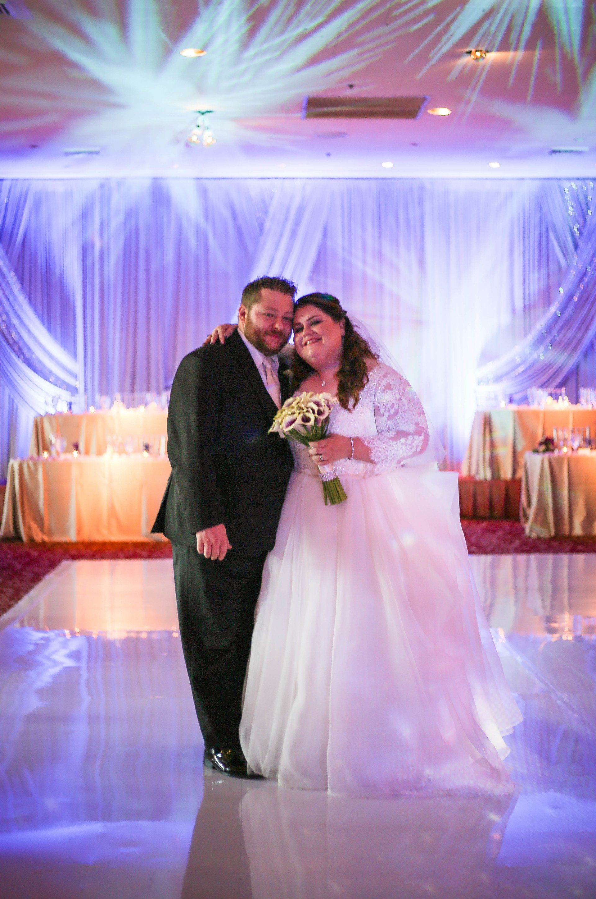 A bride and groom are posing for a picture at their wedding reception.