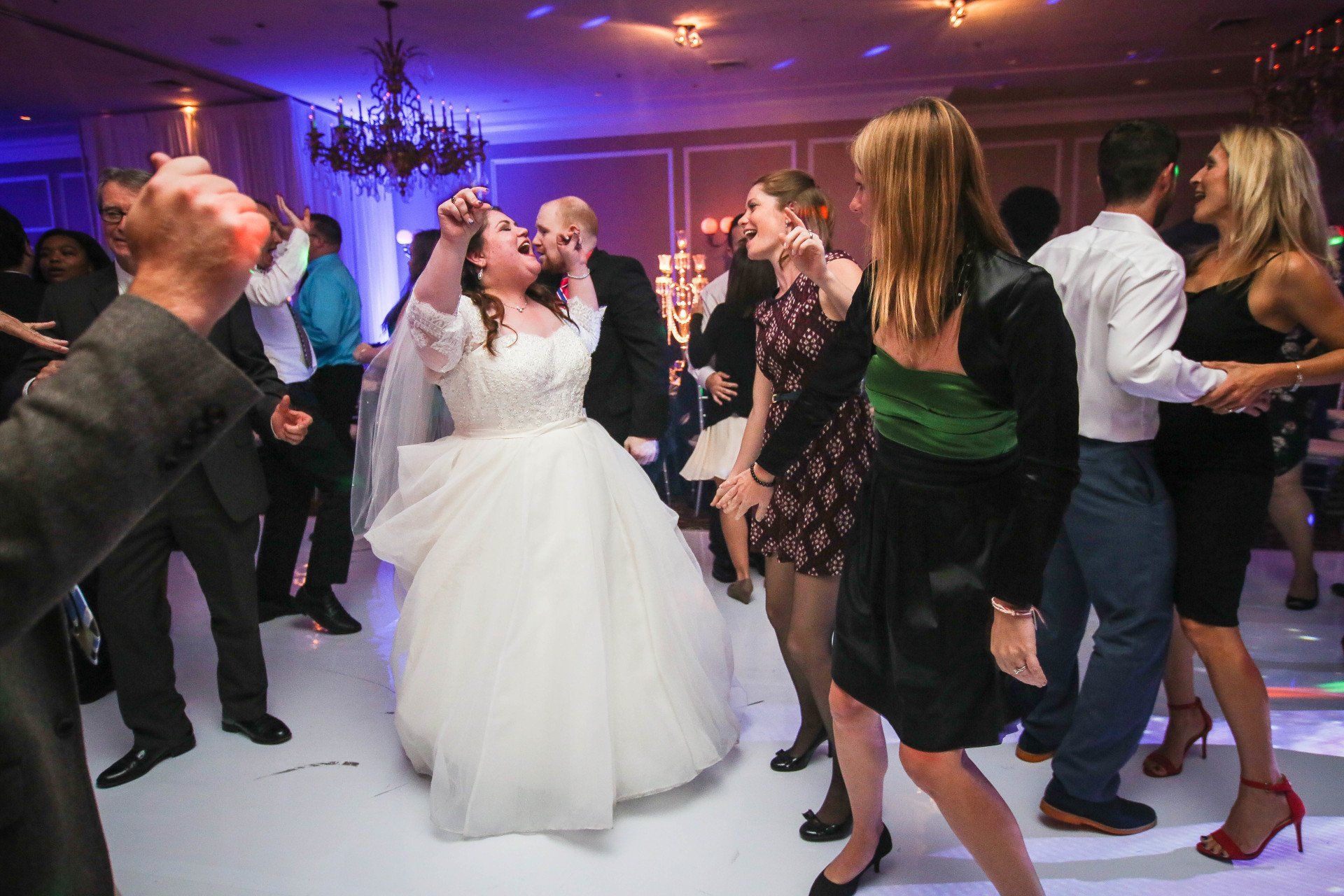 A bride and groom are dancing with their guests at a wedding reception.