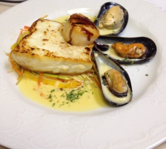 A white plate topped with a piece of fish and mussels