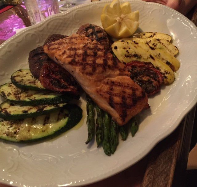 A white plate topped with grilled meat and vegetables
