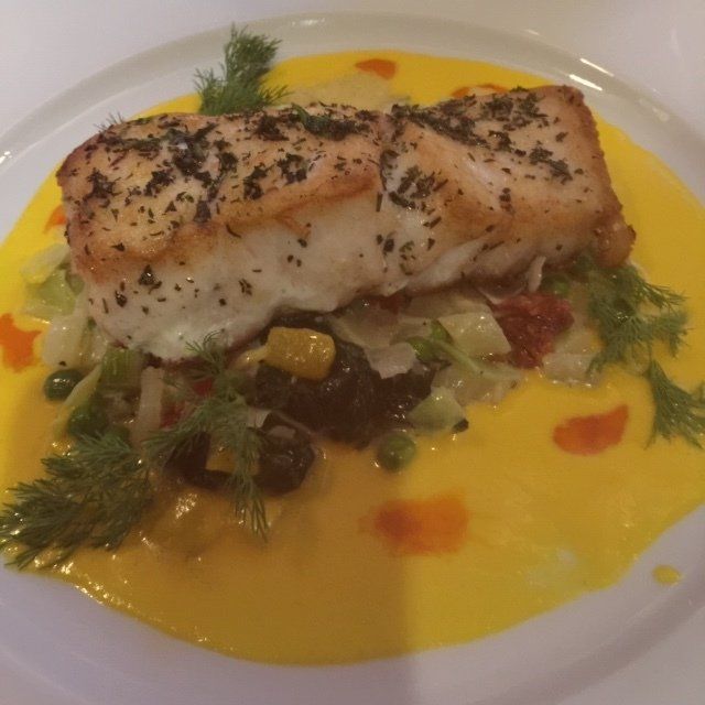 A white plate topped with a piece of fish and vegetables