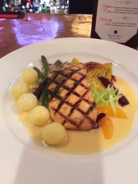 A plate of food with a bottle of wine in the background